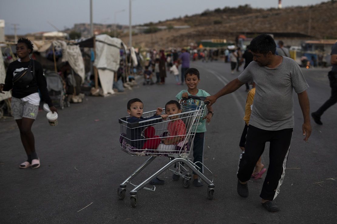 Ein Flüchtling zieht zwei Kinder in einem Einkaufswagen eines Supermarkts in der Nähe der Stadt Mytilini. Nach dem Großbrand im Flüchtlingslager Moria auf Lesbos bleibt die Lage auch nach Öffnung erster Ersatz-Unterkünfte angespannt.&nbsp;Foto: Petros Giannakouris / AP / dpa