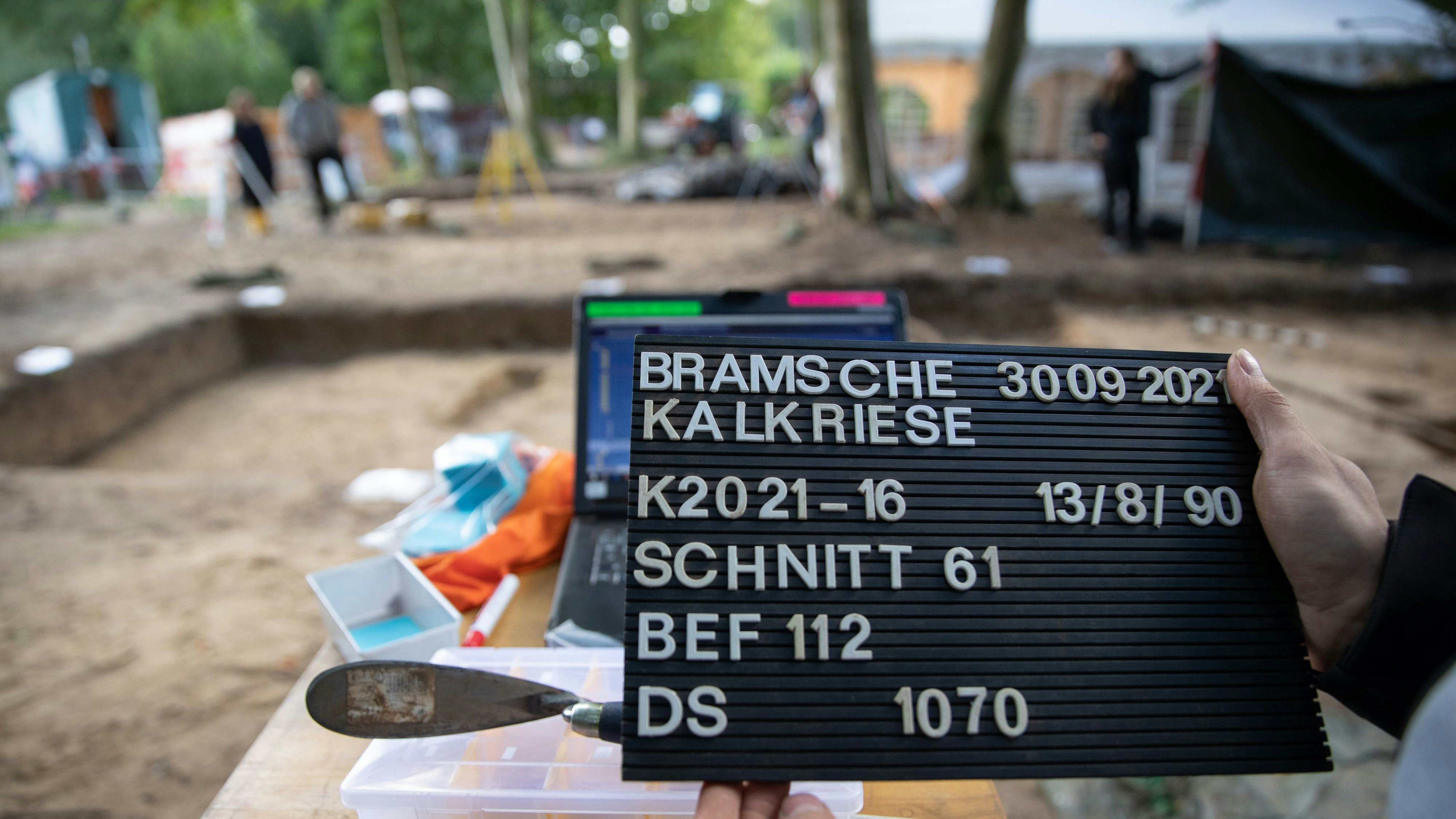 Eine Archäologin hält bei einer archäologischen Grabung auf dem Gelände der Varusschlacht im Osnabrücker Land - Museum und Park Kalkriese eine Fototafel zur Dokumentation eines Grabungsschnitts in der Hand. Foto: dpa