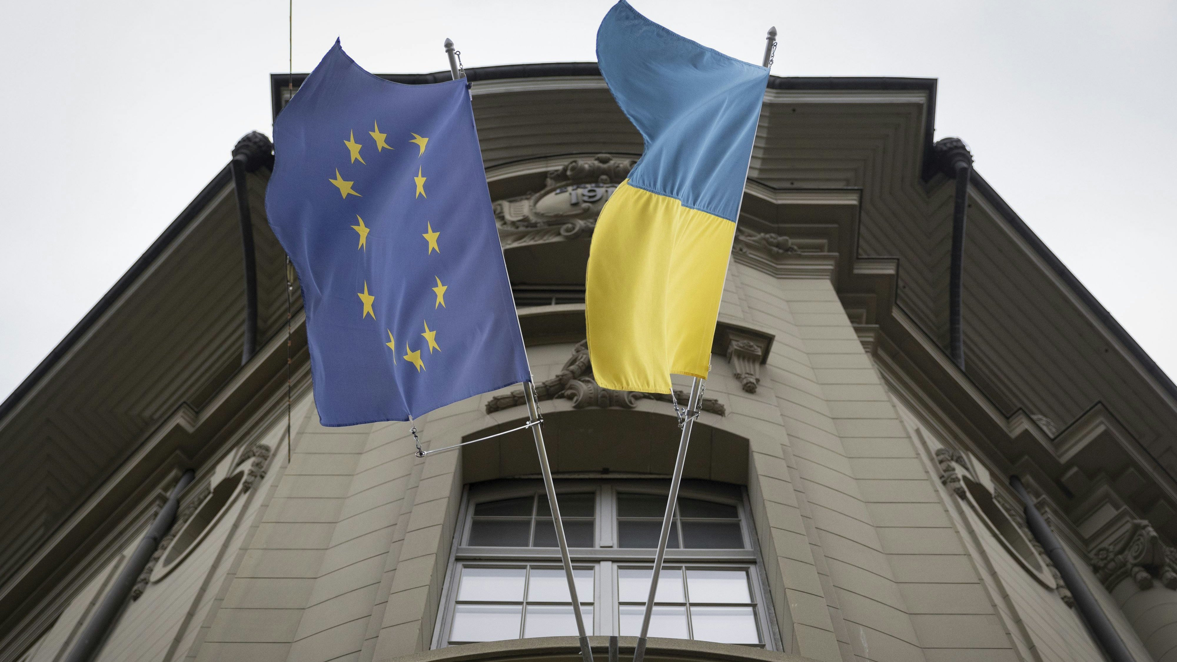Eine Ukrainische Flagge hängt neben einer EU Flagge bei der EU Botschaft in der Nähe des Bundeshauses. Foto: dpa