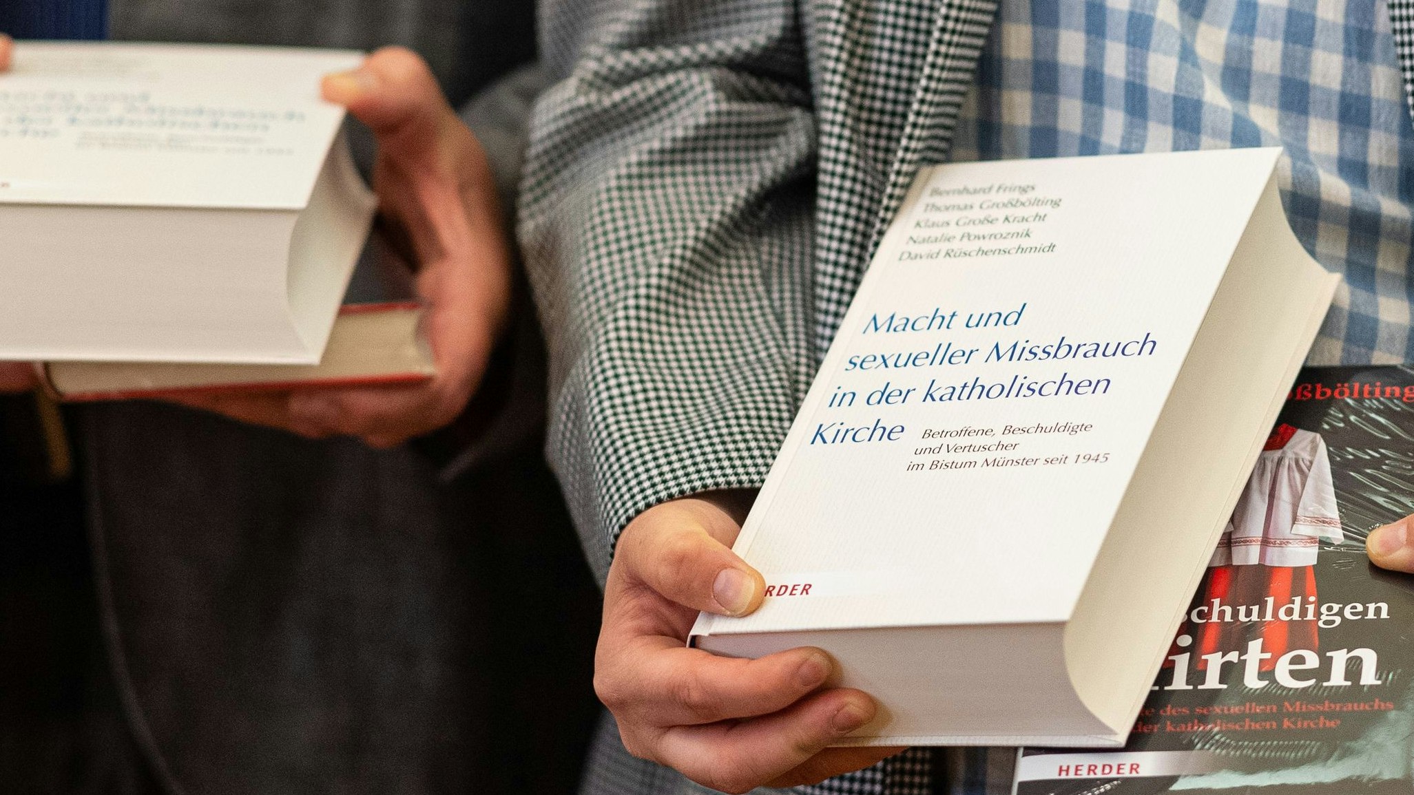 Nach der Pressekonferenz zur Vorstellung der Studienergebnisse zum Missbrauch im Bistum Münster halten zwei Betroffene die Bücher in den Händen. Archivfoto: dpa