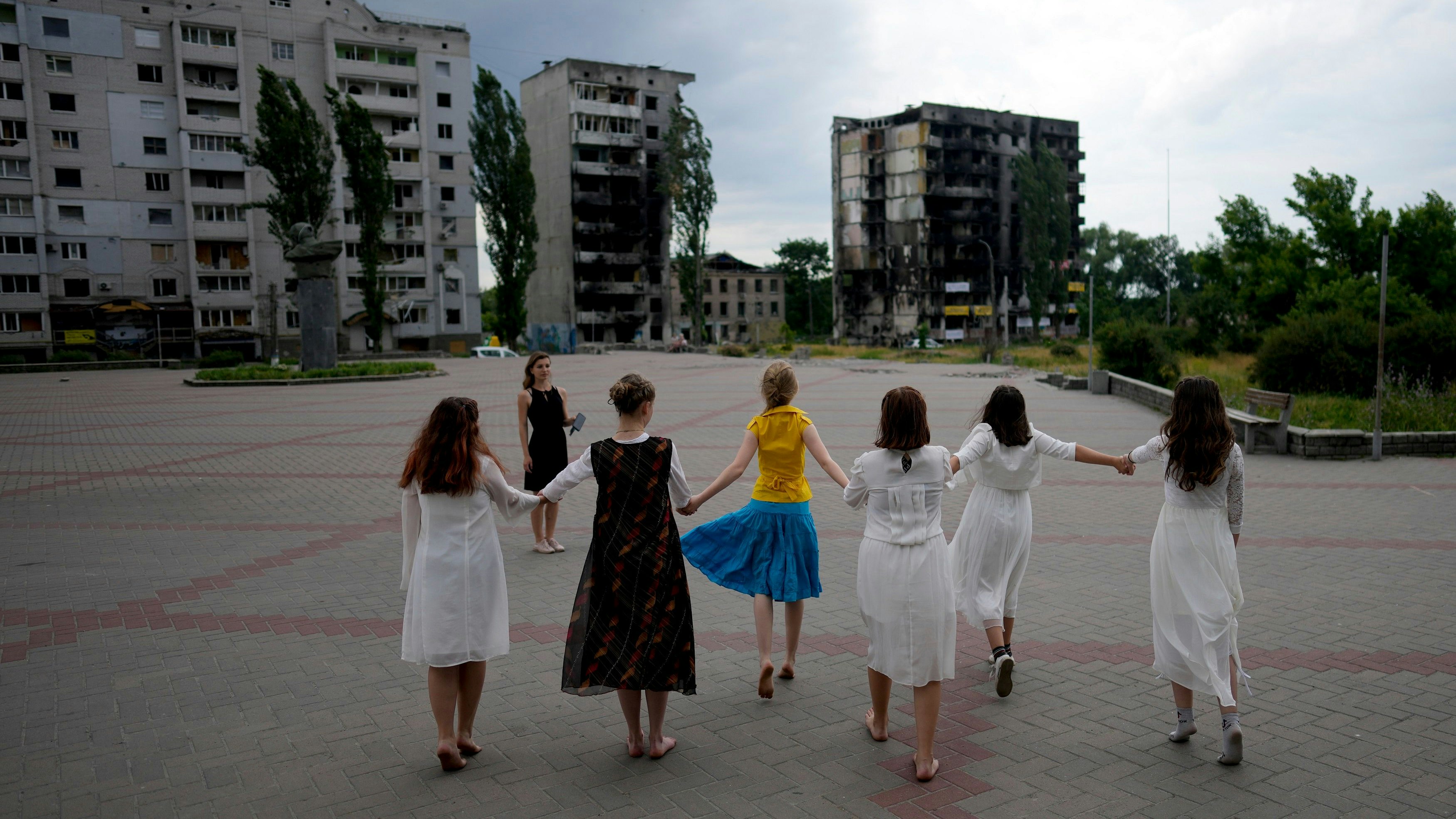Mädchen tanzen in der Nähe eines durch russische Angriffe zerstörten Gebäudes in Borodjanka am Stadtrand von Kiew. Foto: dpa