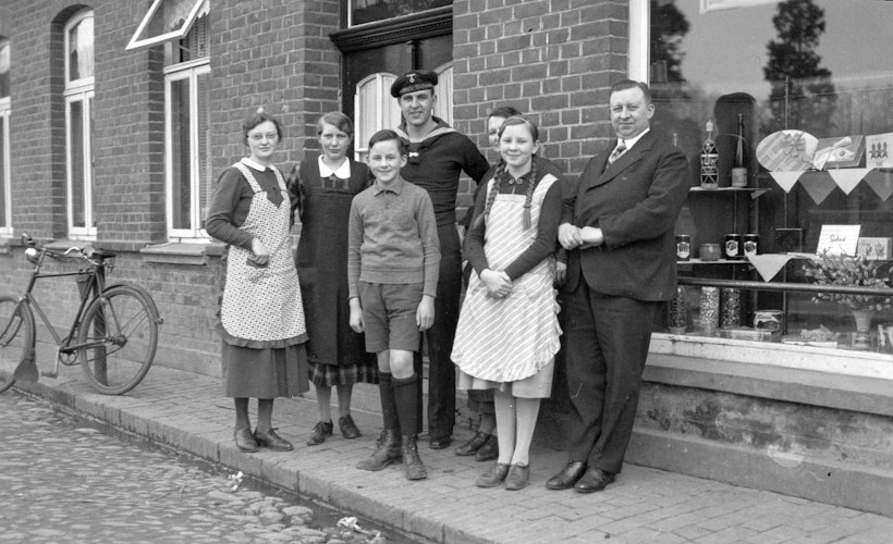 Luise Kunkemöller (links) mit Familie und Matrosenbesuch vor der Gastwirtschaft und dem Colonialwarengeschäft Hermann Borgerding (rechts). Foto: Heimatverein Langförden