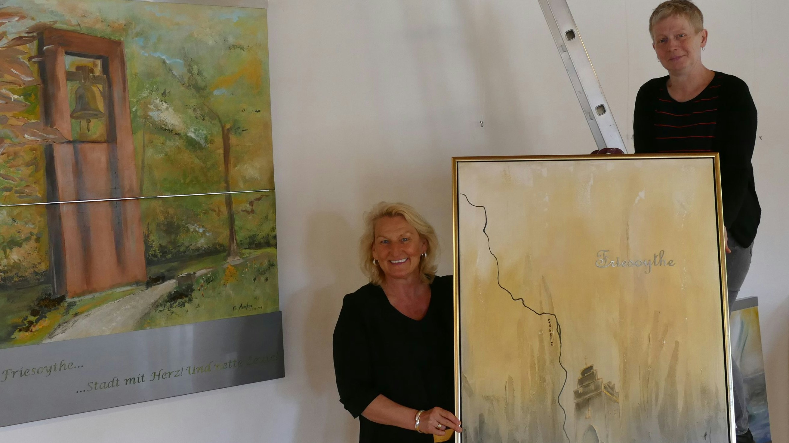 Auftakt: Christa Anneken (links) bestückt ihre Ausstellung in der Wassermühle auch mit Friesoyther Motiven. Beim Aufhängen der Werke hilft Sabine Winnat vom Kulturzentrum. Foto: Stix