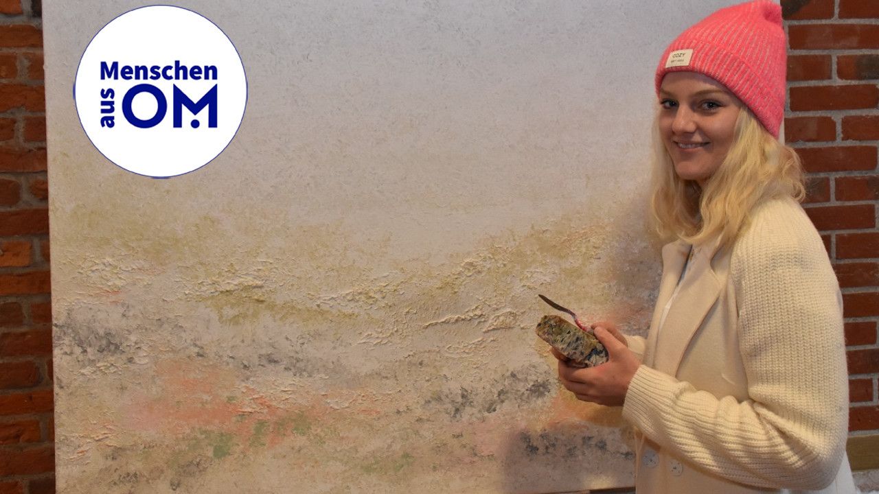 Mit Schwamm und Spachtel: Künstlerin Antonia Heckmann vor ihrem Gemälde „Worte des Friedens“, das sie zugunsten der Ukraine veräußern möchte. Foto: Klöker