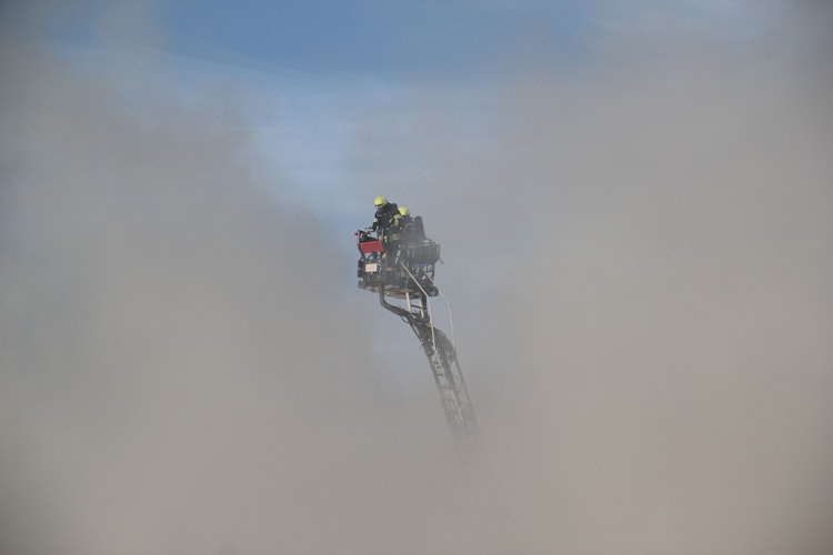 Mitten im Qualm: Die Feuerwehr arbeitete auch mit den Drehleitern unter Hochdruck und verhinderte ein Übergreifen der Flammen auf umliegende Gebäude. Foto: Speckmann