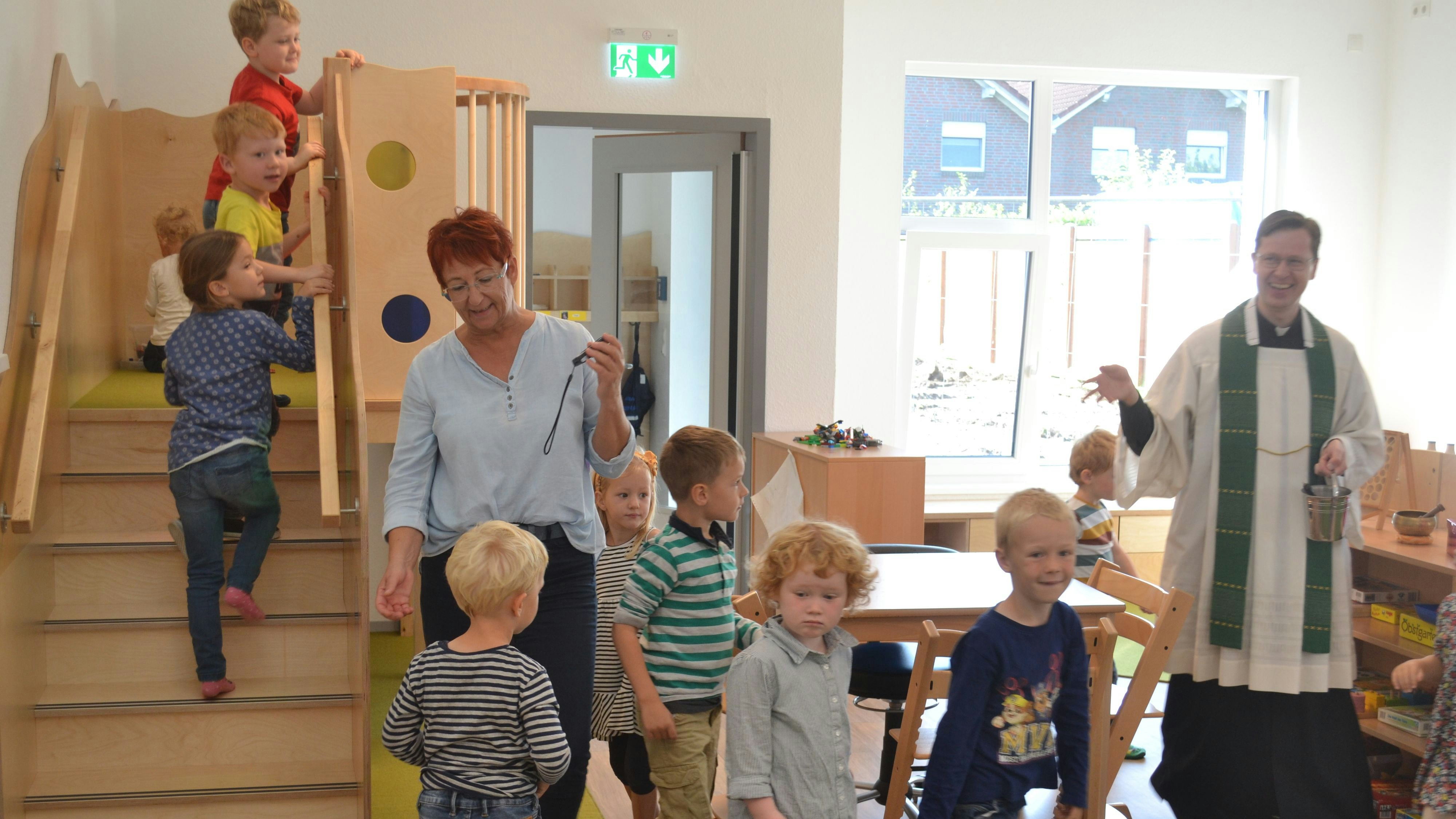 Einweihung: Pfarrer Jörn Illenseer und Kita-Mitarbeiterin Bernadette Thole gingen mit den Kindern durch die Räume.&nbsp; Foto: Schrimper