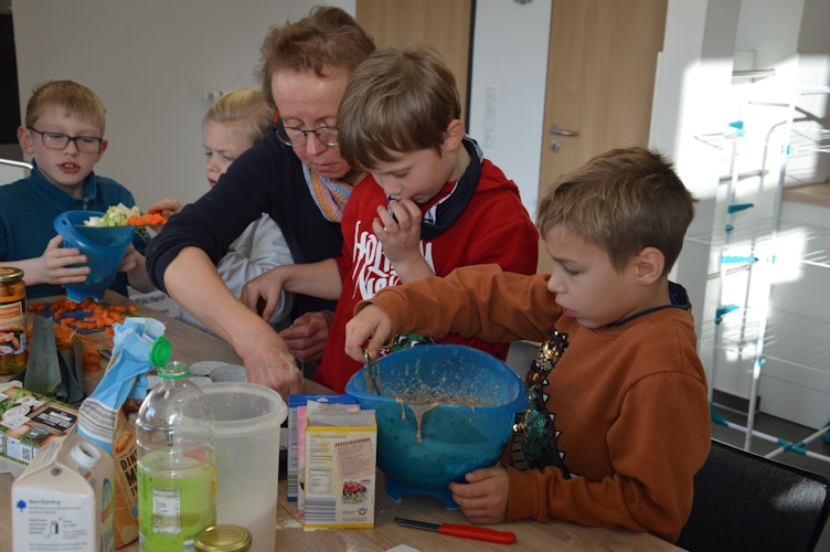 Bringt den Teig in die Form: Kursleiterin Mechthild Waller (Mitte) ist da, wenn die Kinder Hilfe brauchen. Foto: Wienken