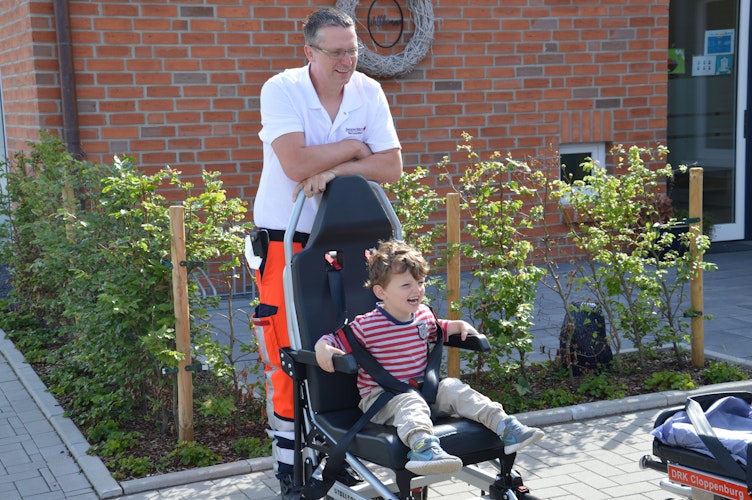 Wie ein echter Patient: Josef Völker dreht mit den Kindern eine Runde im Rollstuhl. Foto: Wienken