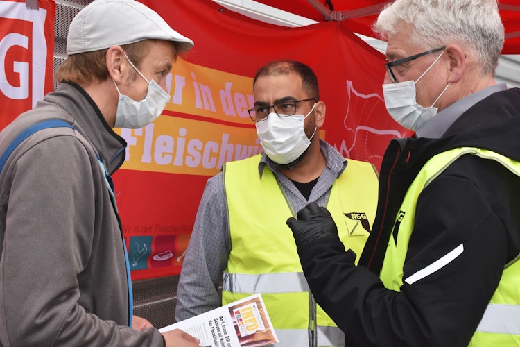 Einer von insgesamt 10.000: Die Gewerkschafter Matthias Brümmer (rechts) und Ibrahim Ergin (Mitte) im Gespräch mit einem Mitarbeiter aus der Fleischindustrie, in diesem Fall OGS. Foto: Berg