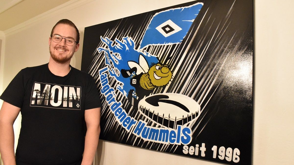 Ist zuversichtlich, dass in diesem Jahr der Aufstieg gelingt: Tim Weustermann mit dem auf Leinwand gebrachten Logo des HSV-Fanclubs „Langfördener Hummels“. Foto: Klöker