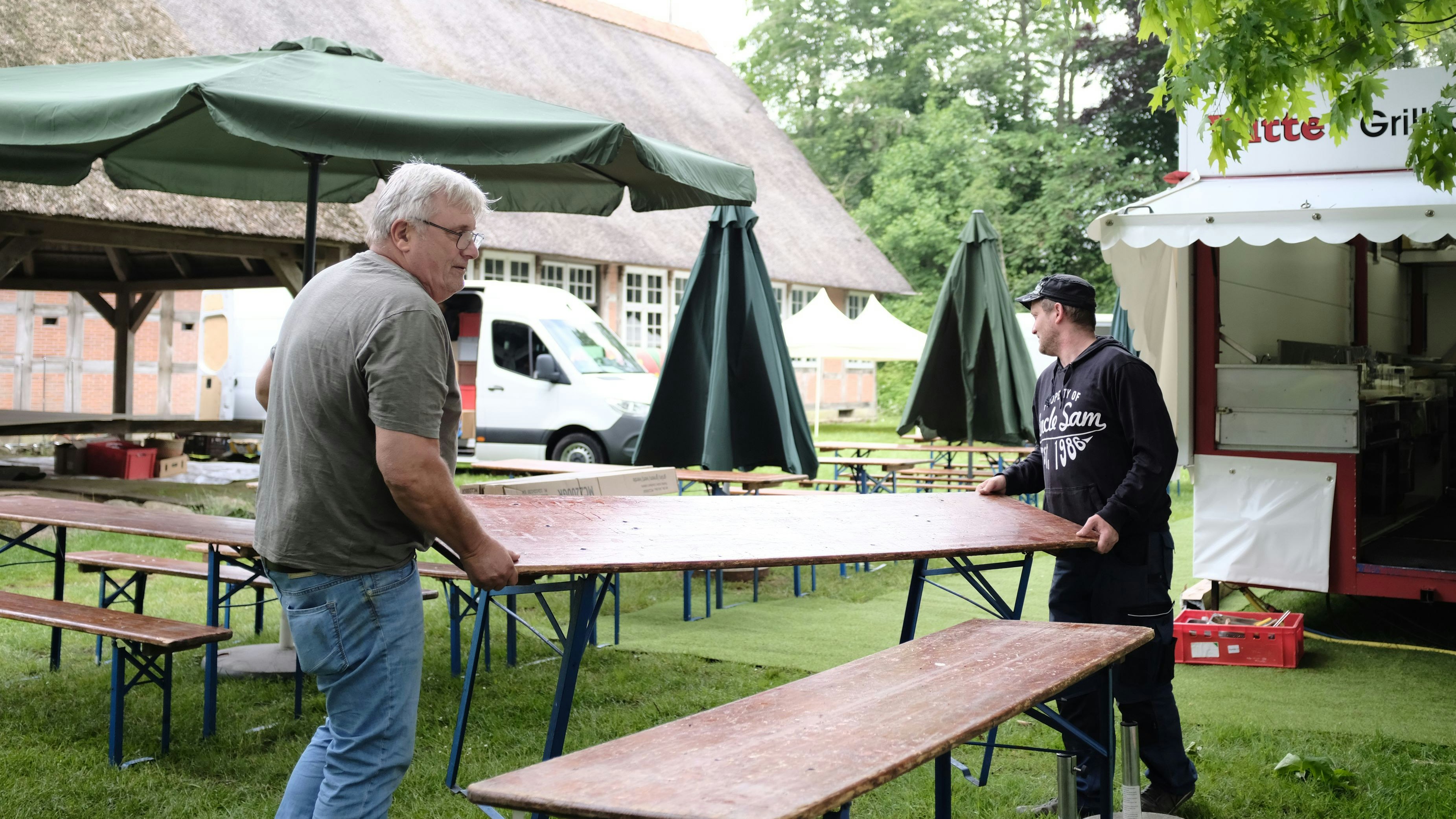 Die letzten Vorbereitungen laufen: Georg Witte (links) und Alexander Gercke bauen 2 Tage vor Beginn der Dorfpartie Bänke und Tische vor ihrem Grillwagen auf. Foto: Niemeyer