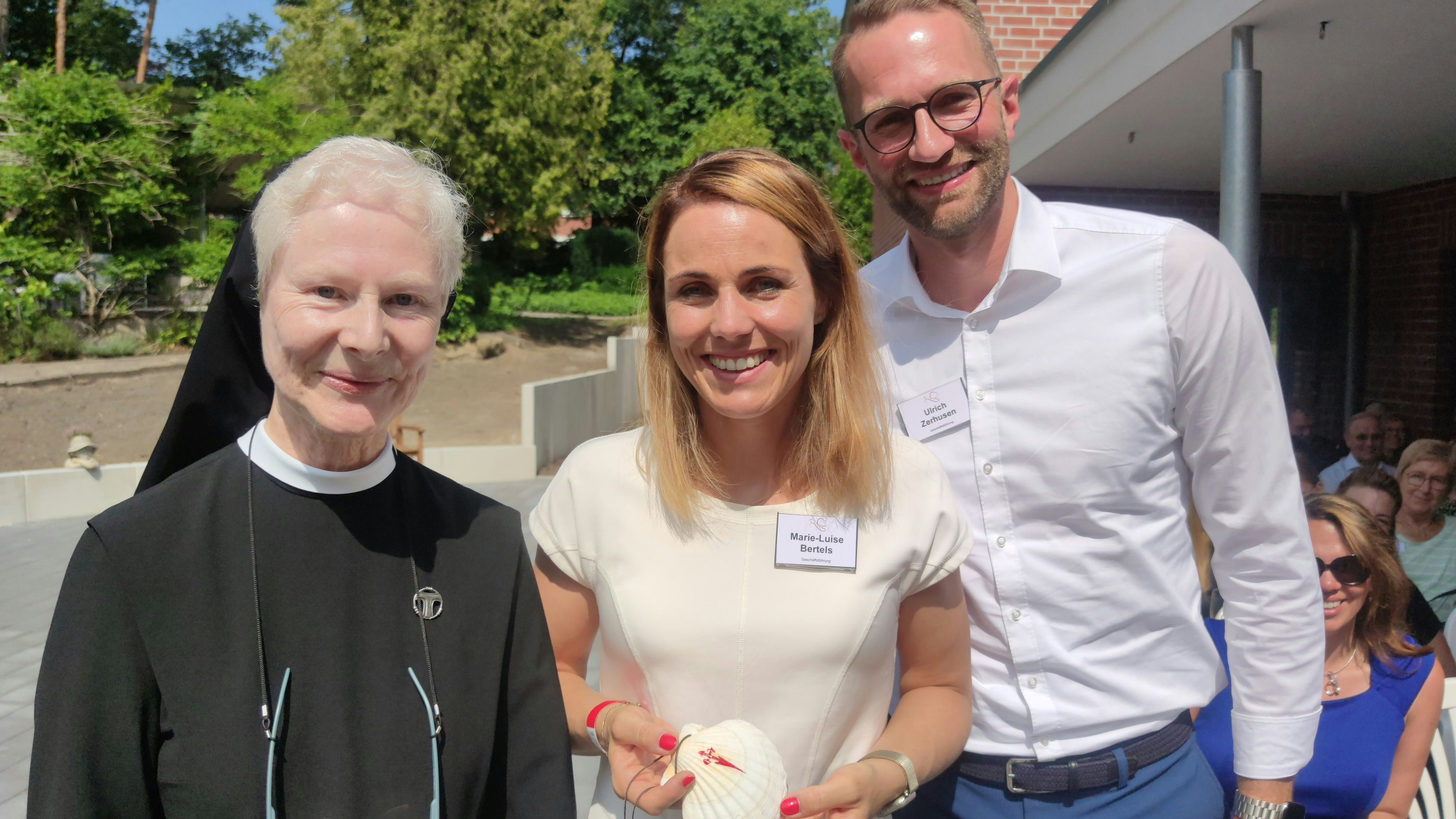 Schwester Marianne (links) schenkt Marie-Luise Bertels und Ulrich Zerhusen eine Jakobsmuschel zur Einweihung des Hauses am Jakobsweg. Foto: Röttgers