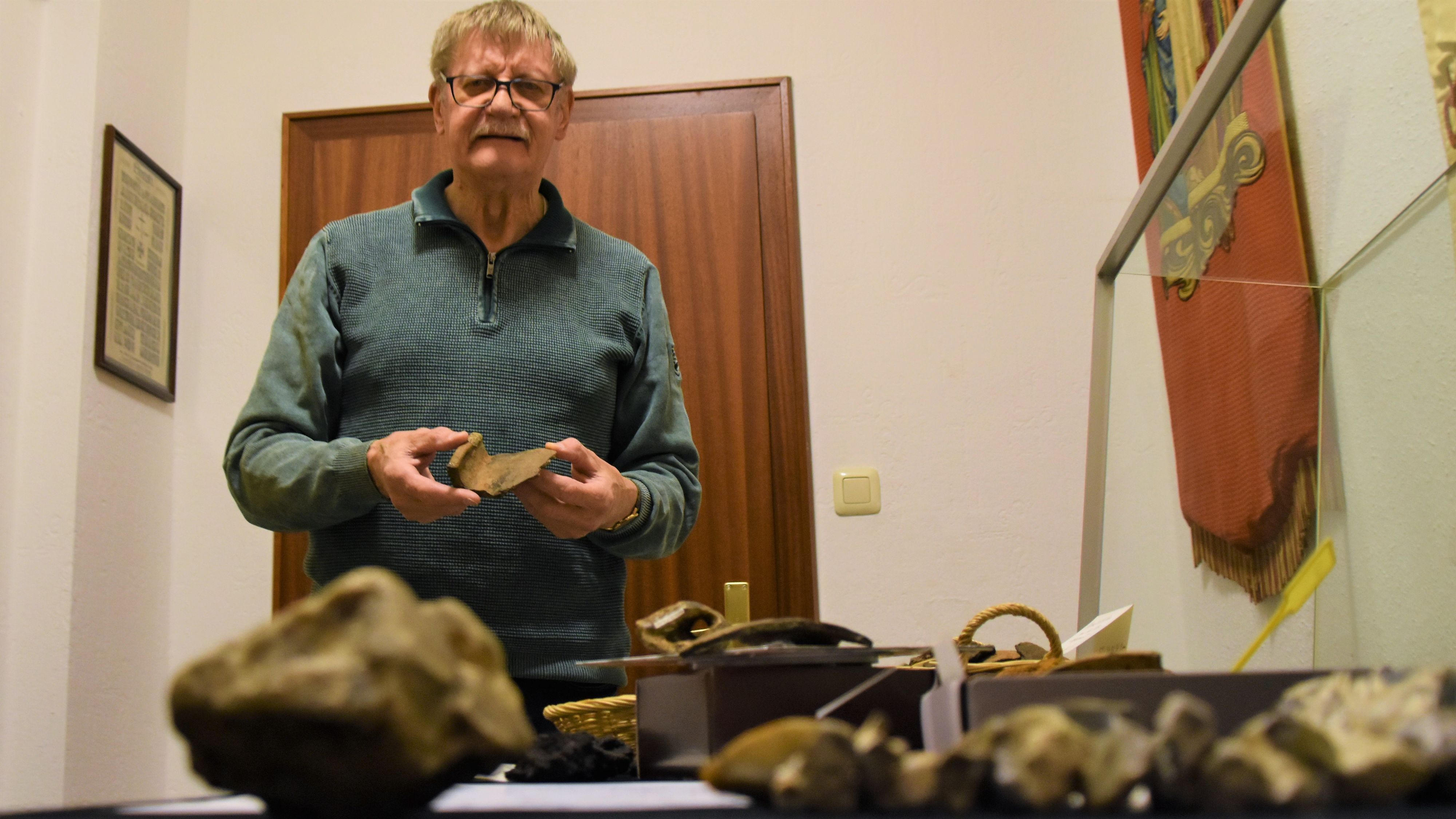 Spannender Fund: Heinz Frerichs mit einer Tonscherbe, die aus dem 9. Jahrhundert stammt und nun im Heimathaus Harkebrügge in einer Vitrine ausgestellt ist. Foto: Hahn
