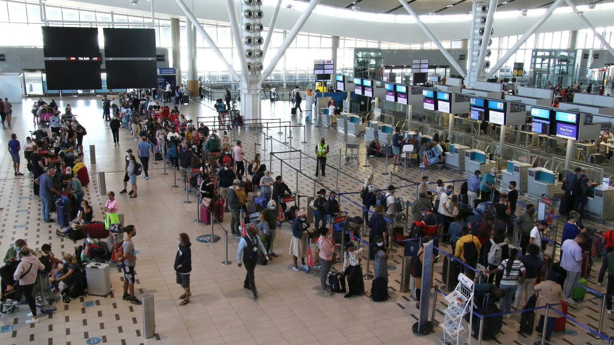 Reisende stehen am Flughafen in Kapstadt in langen Schlangen an den wenigen Schaltern an, die überhaupt noch offen sind. Foto: dpa/Palitza