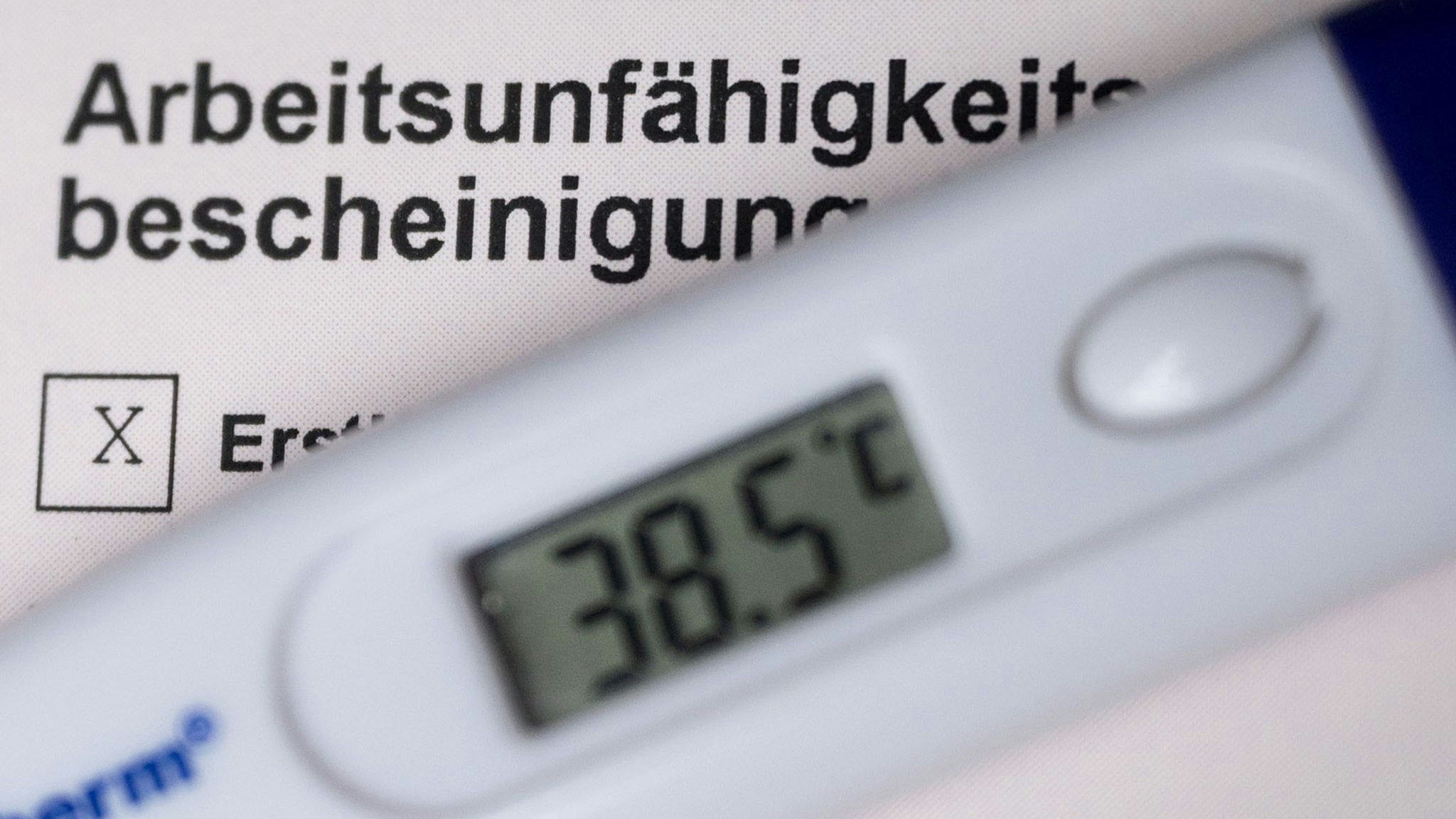 Ein Fieberthermometer liegt auf einer Arbeitsunfähigkeitsbescheinigung. Foto: dpa/Murat