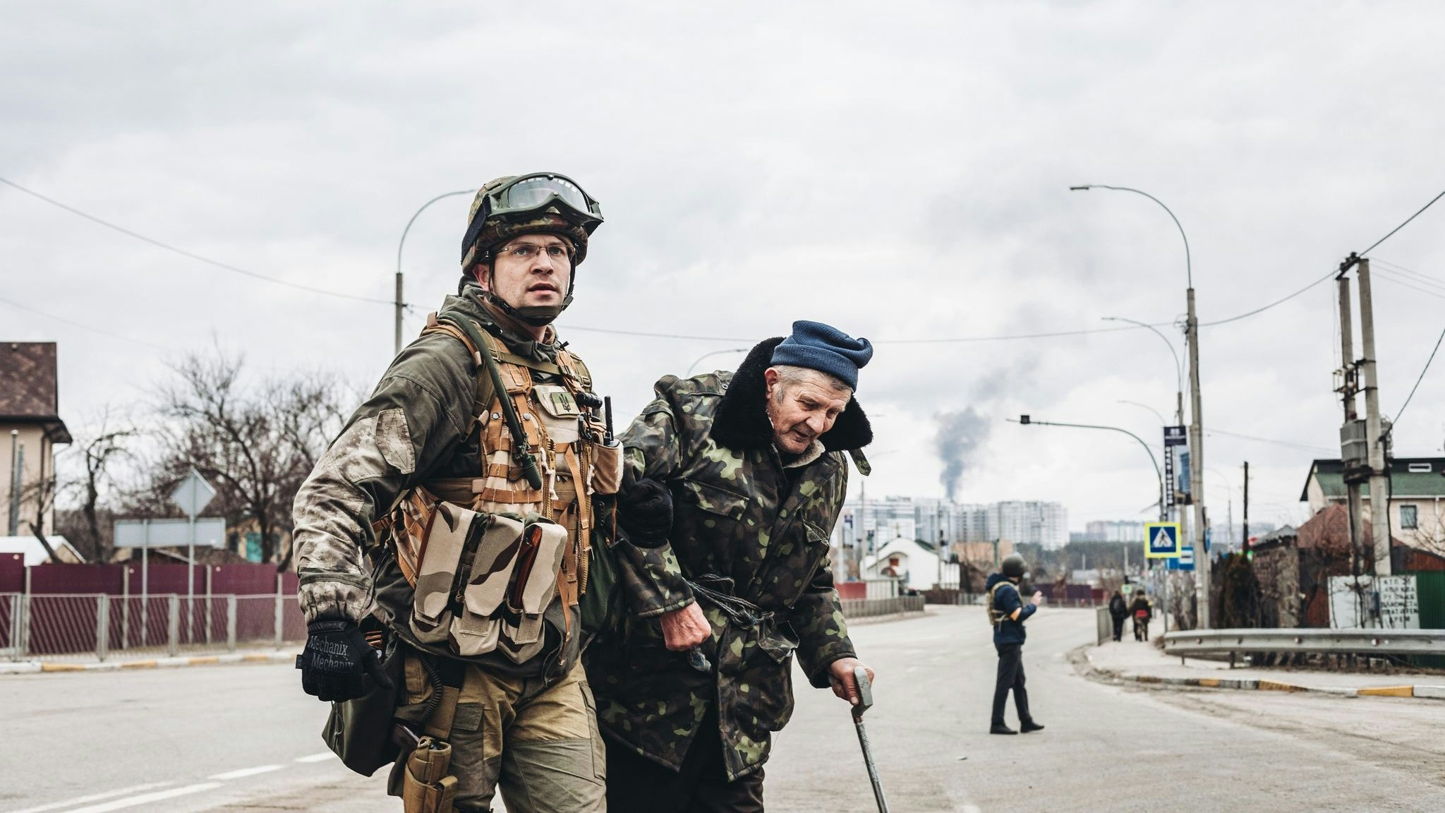 Ein ukrainischer Soldat in Irpin hilft einem älteren Mann, die Straße zu überqueren. Foto: dpa/Herrera