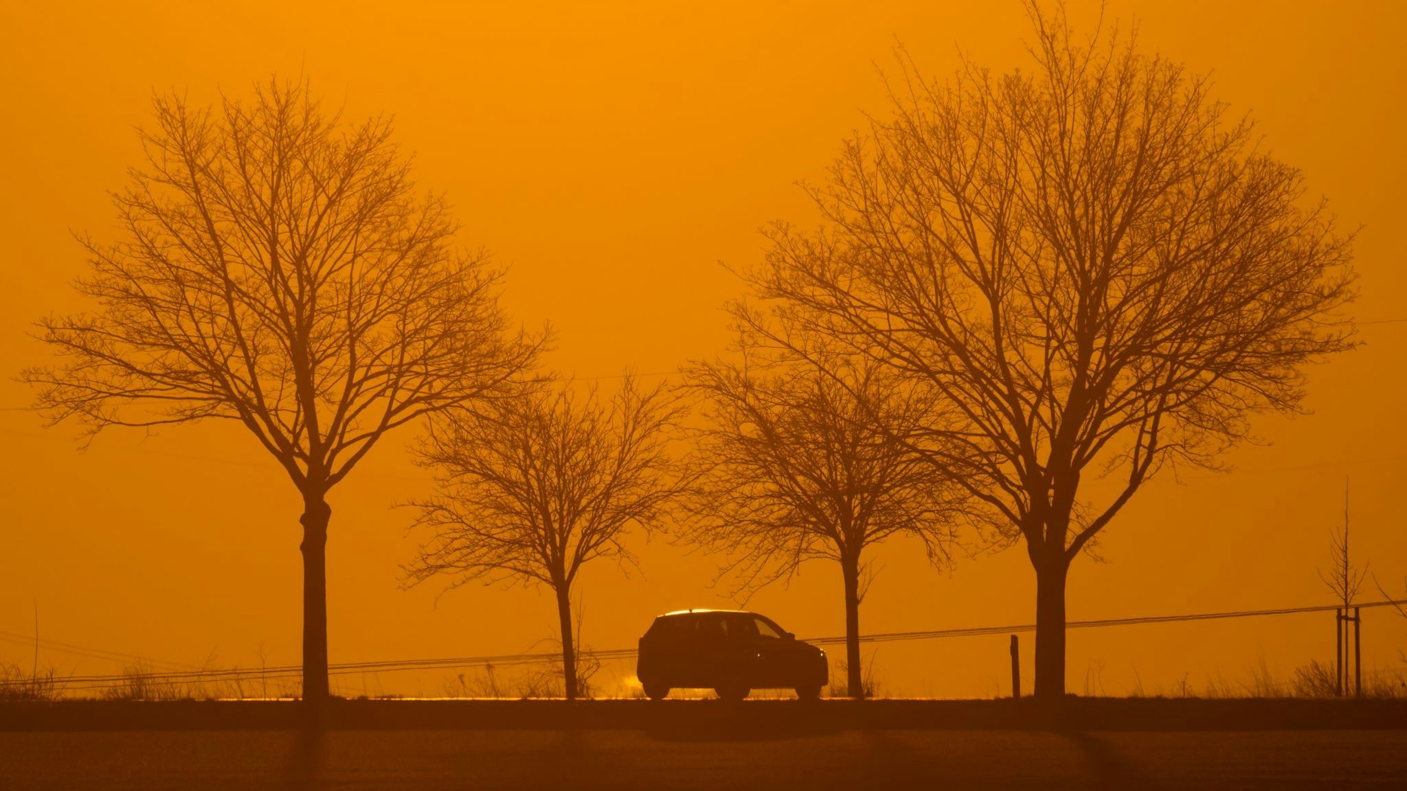Ein Auto fährt im Licht der aufgehenden Sonne über eine Landstraße in der Region Hannover. Foto: dpa/Stratenschulte