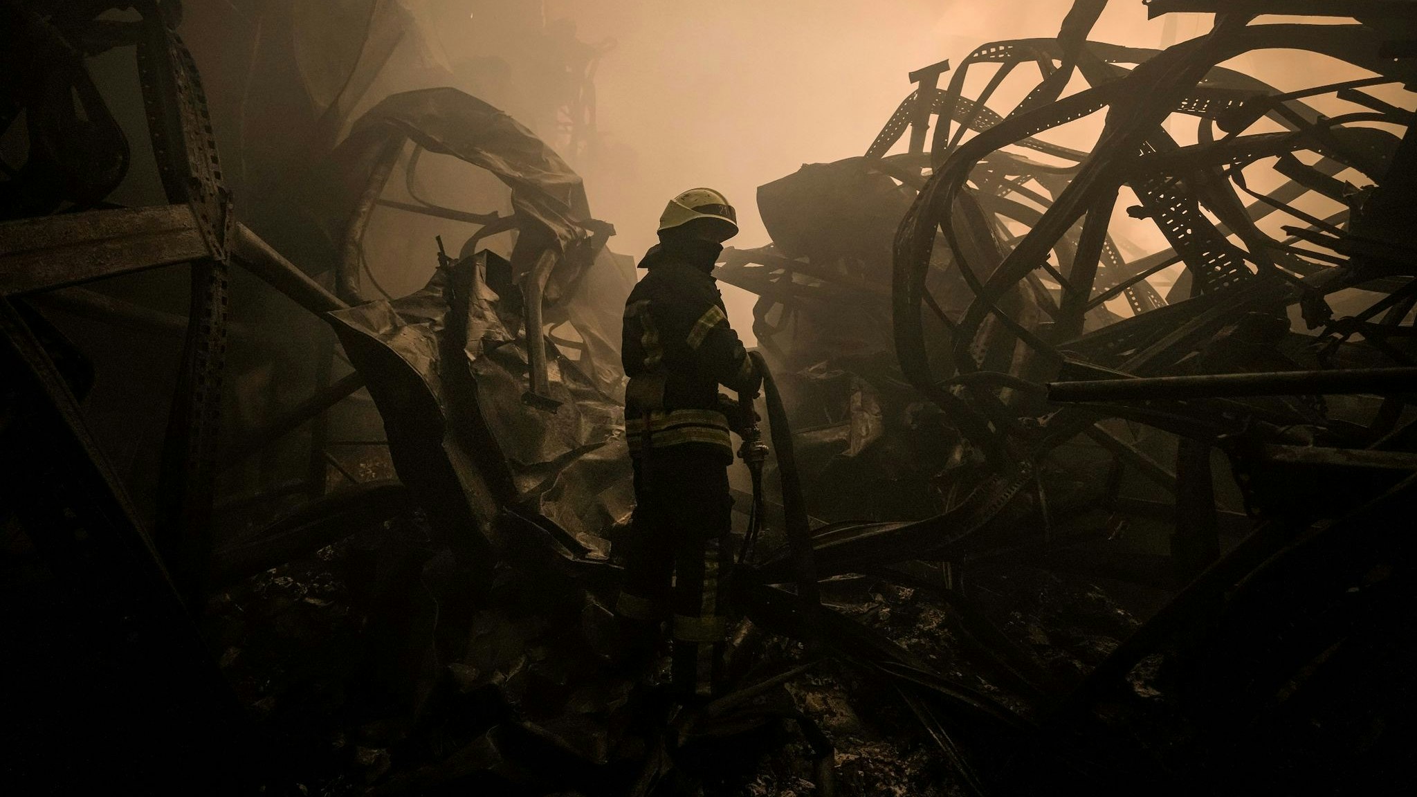 Ein ukrainischer Feuerwehrmann zieht einen Schlauch durch ein großes Lebensmittellager am Stadtrand von Kiew, das durch einen Luftangriff zerstört wurde. Foto: Vadim Ghirda / AP / dpa 
