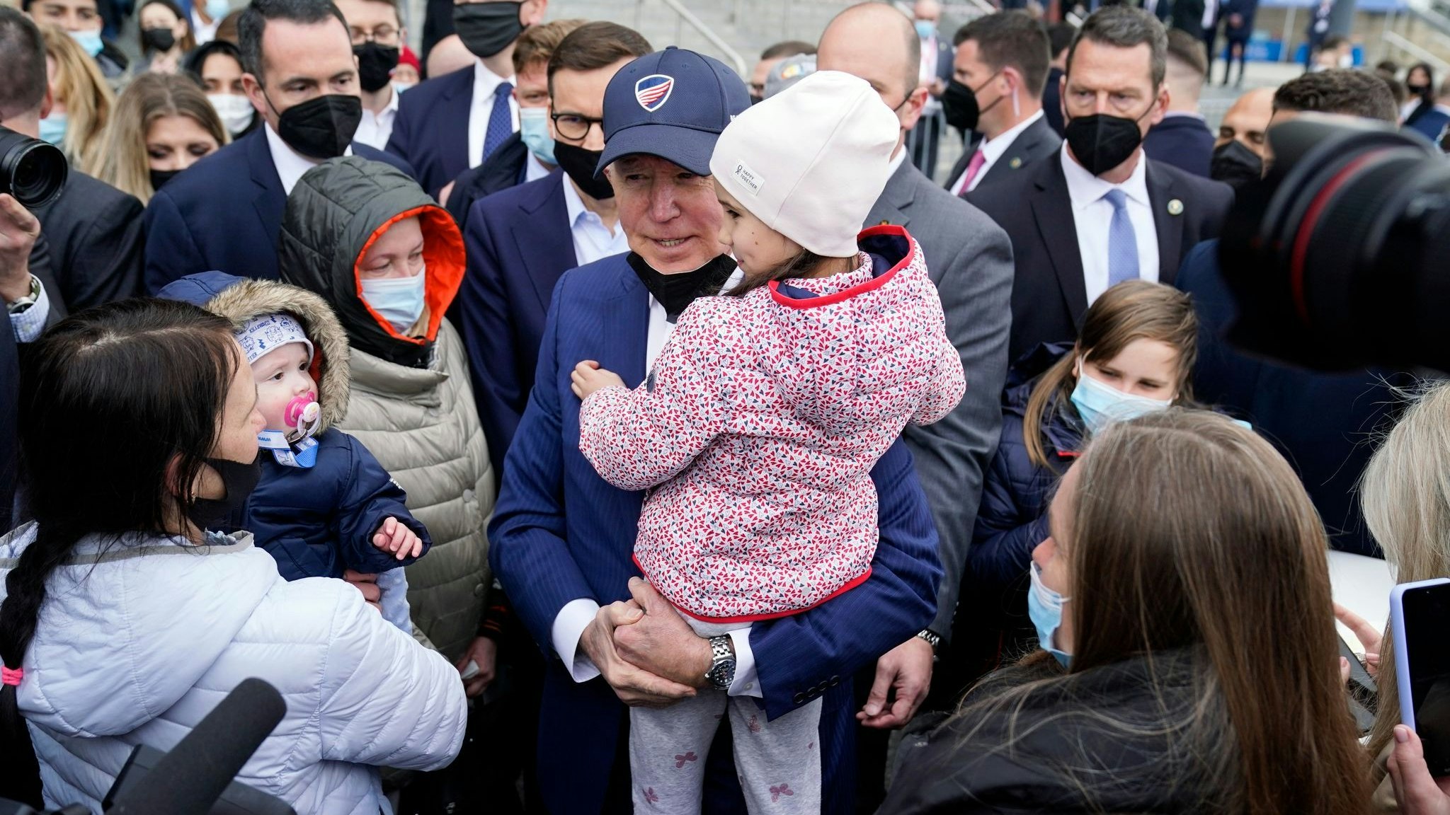Besuch in Notunterkunft: Joe Biden trägt bei seinem Besuch im PGE Narodowy-Stadion, in dem ukrainische Kriegsflüchtlinge untergebracht sind, ein Kind. Foto: dpa/AP/Vucci