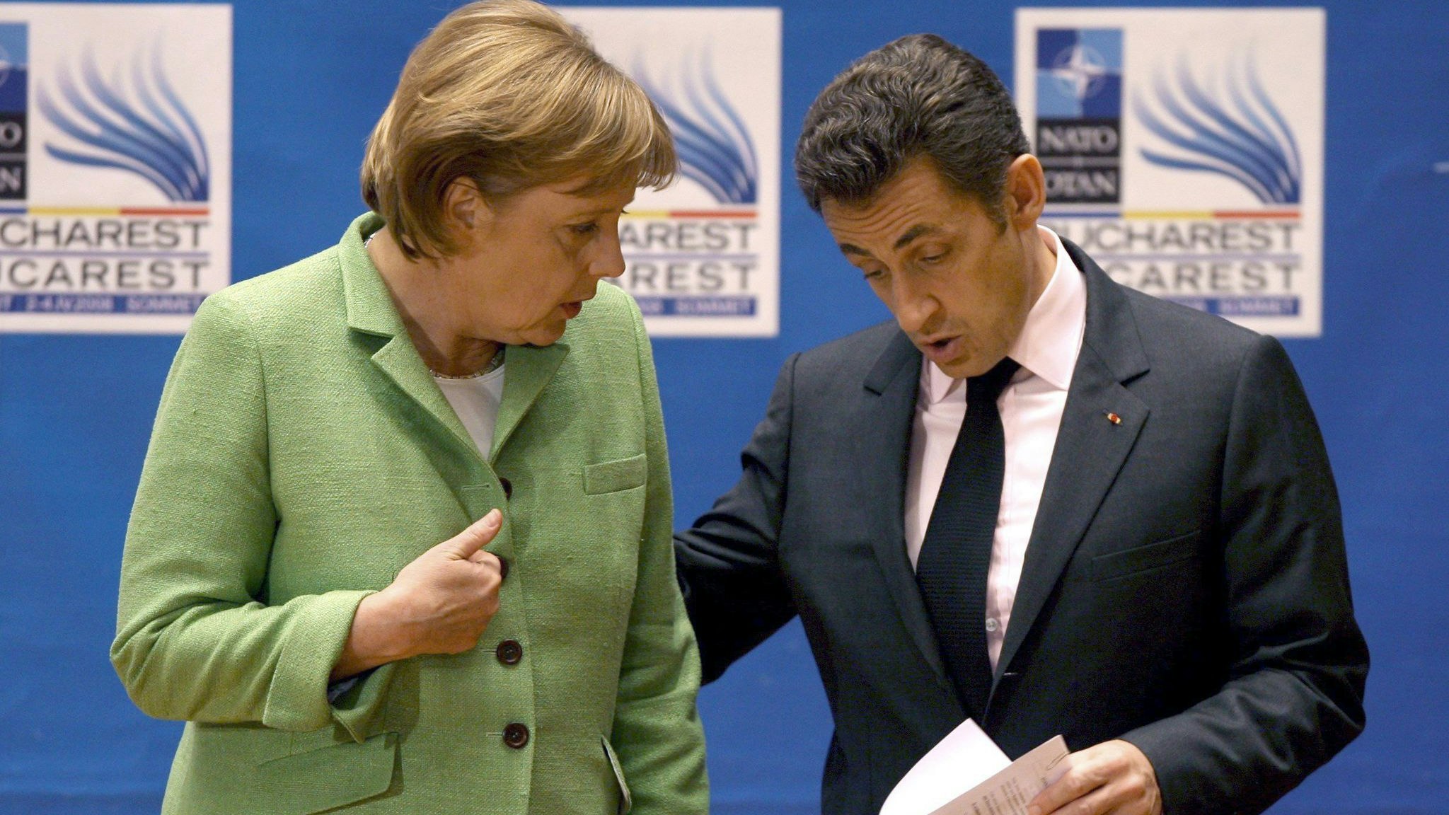 Die damalige Bundeskanzlerin Angela Merkel (l, CDU) spricht mit Nicolas Sarkozy, damals Präsident von Frankreich, am Ende der Eröffnungssitzung des NATO-Gipfels. Foto: dpa/epa/Ghement