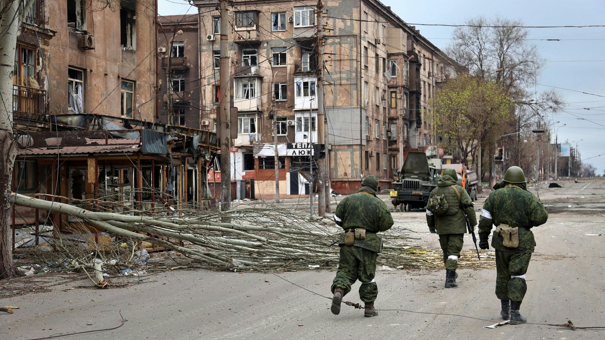 Soldaten der Miliz der „Volksrepublik“ Donezk gehen an beschädigten Wohnhäusern in Mariupol vorbei. Foto: dpa/Alexandrov