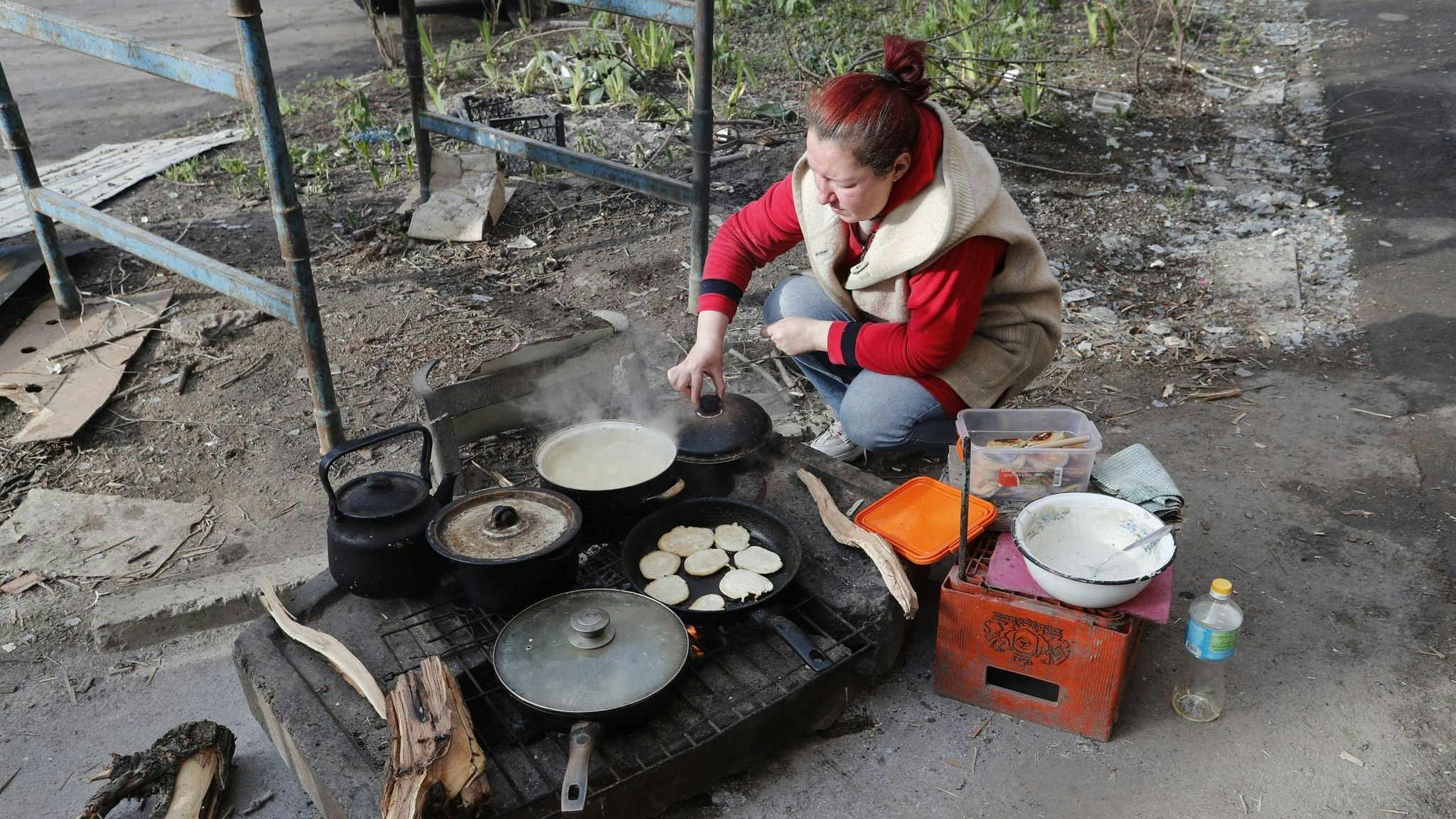 Eine Anwohnerin in Mariupol kocht am Straßenrand Essen. Die Hafenstadt Mariupol ist seit dem 1. März vollständig von russischen Truppen eingeschlossen. Foto: dpa/Victor