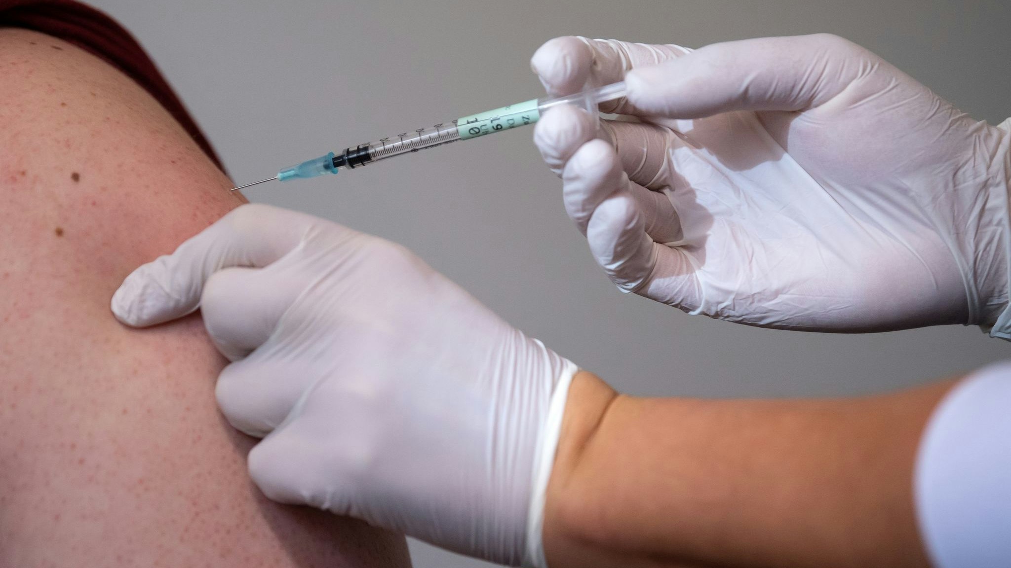 Eine Mitarbeiterin eines Impfzentrums impft einen Mann gegen Corona. Foto: dpa/Hoppe