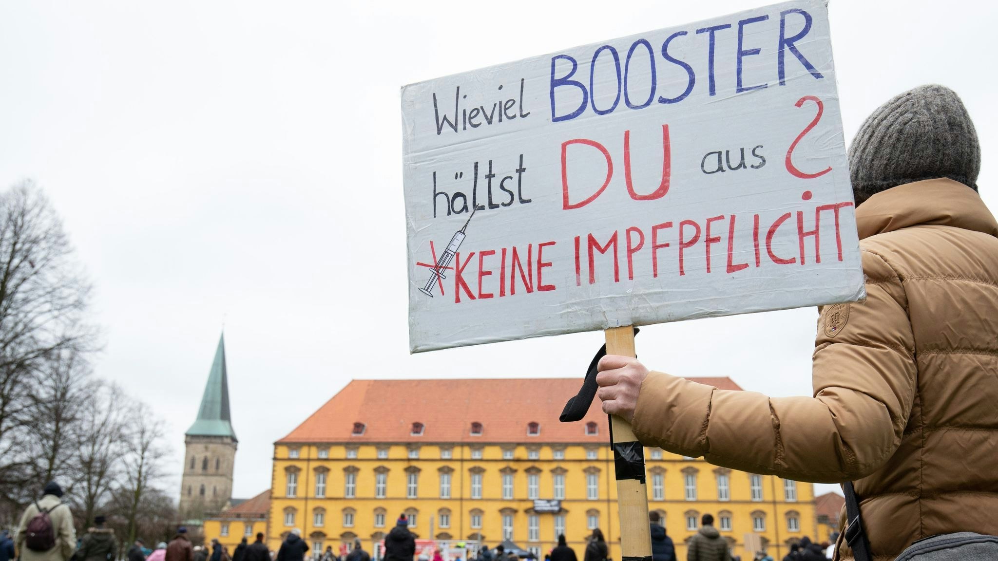 Eine Teilnehmerin hält ein Plakat mit der Aufschrift „Wieviel Booster hältst du aus? Keine Impfpflicht“. Foto: dpa/Gentsch