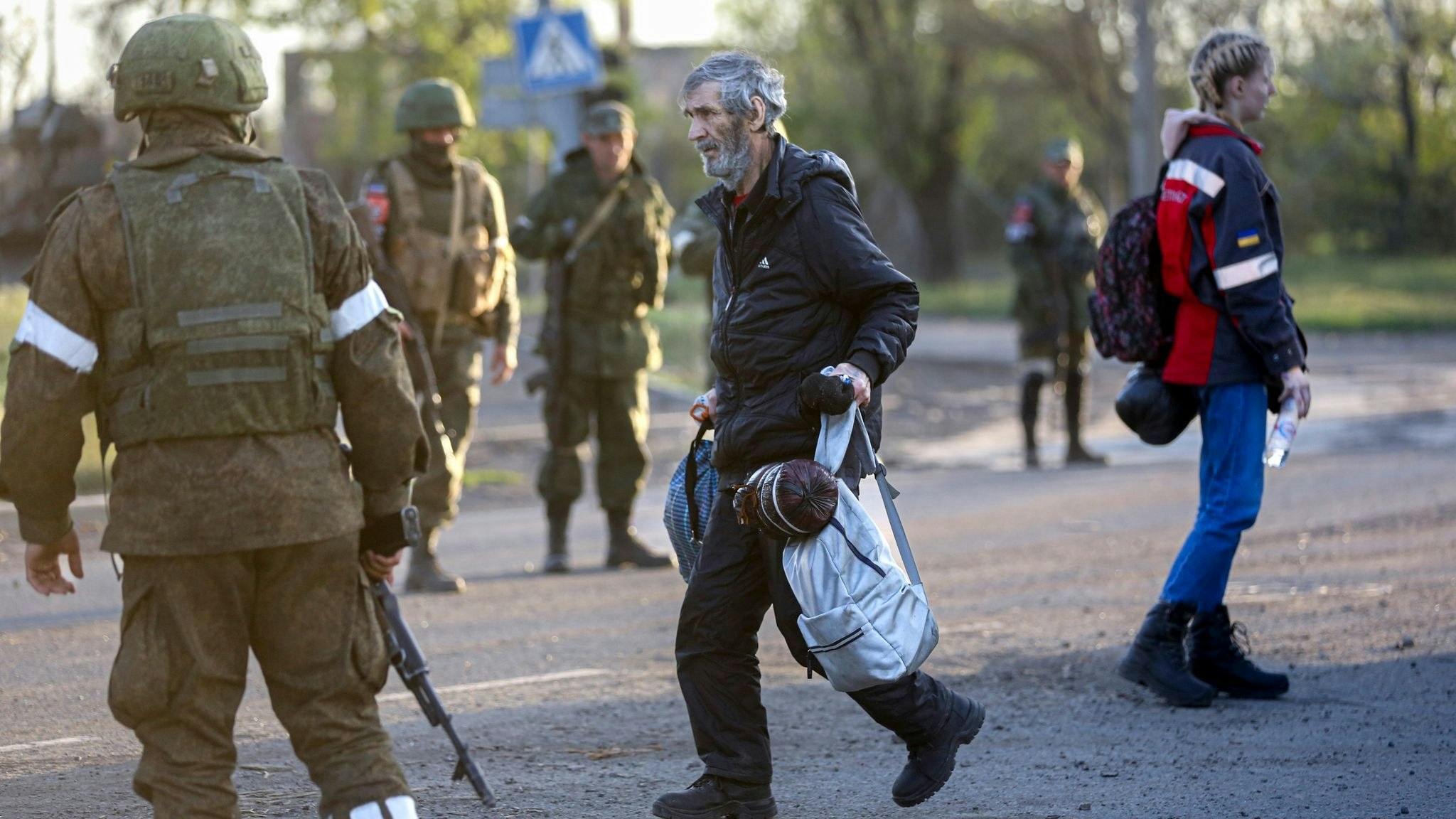 Ein aus dem Stahlwerk Asovstal entkommener Mann läuft an Soldaten der russischen Armee und der Miliz der „Volksrepublik“ Donezk vorbei. Foto: Alexei Alexandrov / AP / dpa