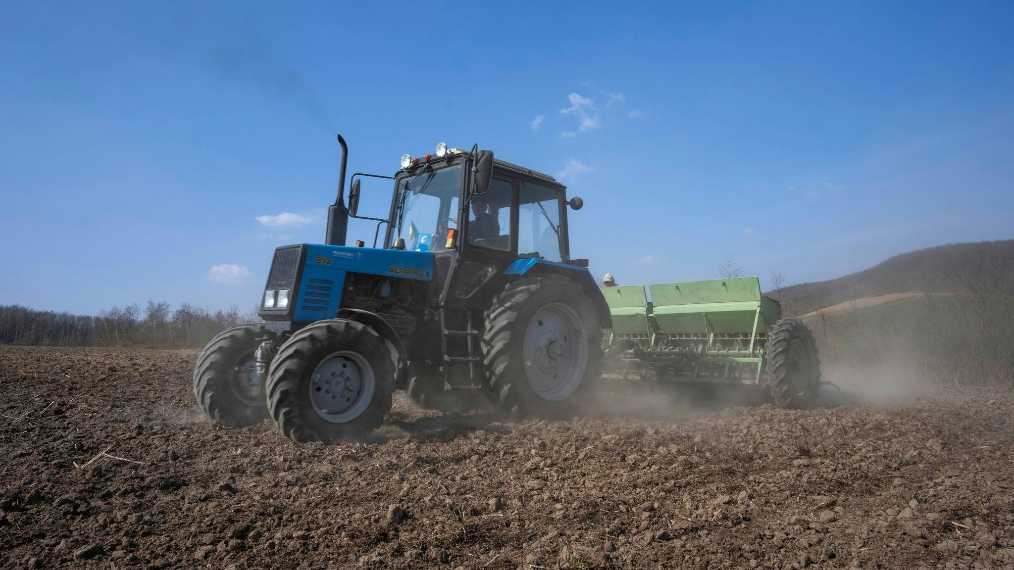 Arbeiter pflügen ein Weizenfeld im Westen der Ukraine. Foto: Nariman El-Mofty / AP / dpa