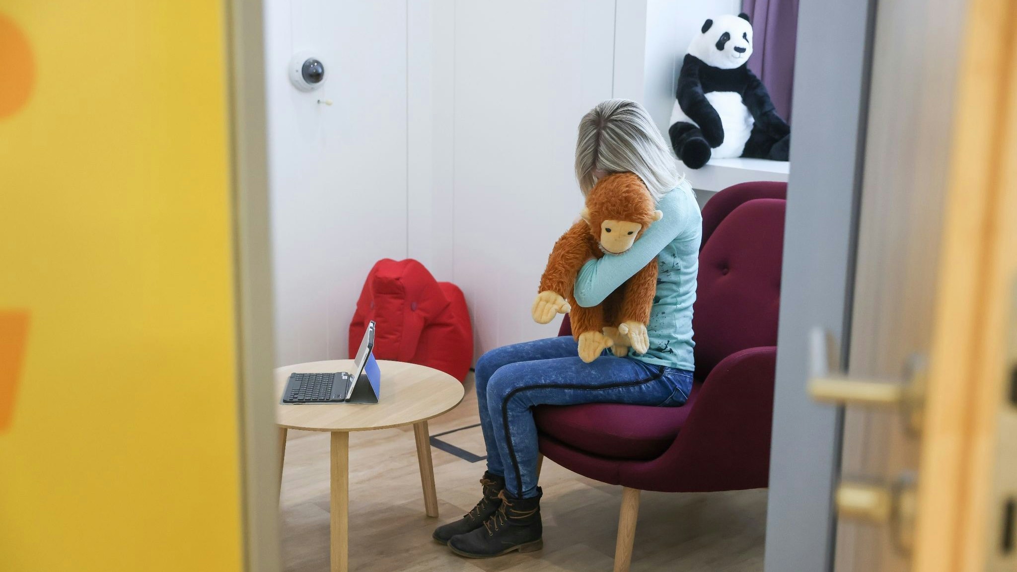 Ein Kind sitzt in einem Gesprächszimmer und umklammert ein Plüschtier. Foto: dpa/Woitas