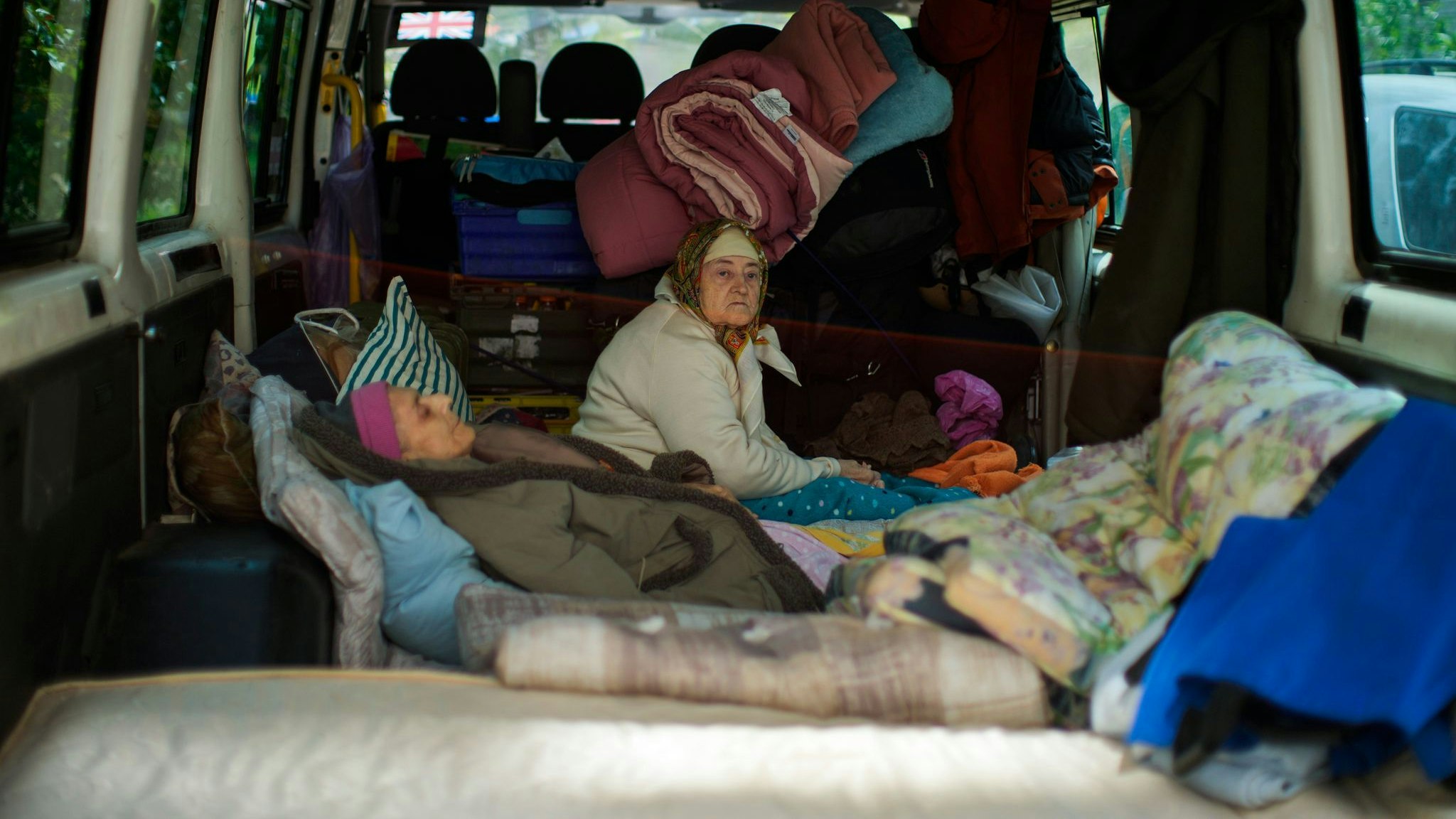 Zwei Frauen sitzen in Bachmut in einem Lieferwagen. Foto: dpa/Seco