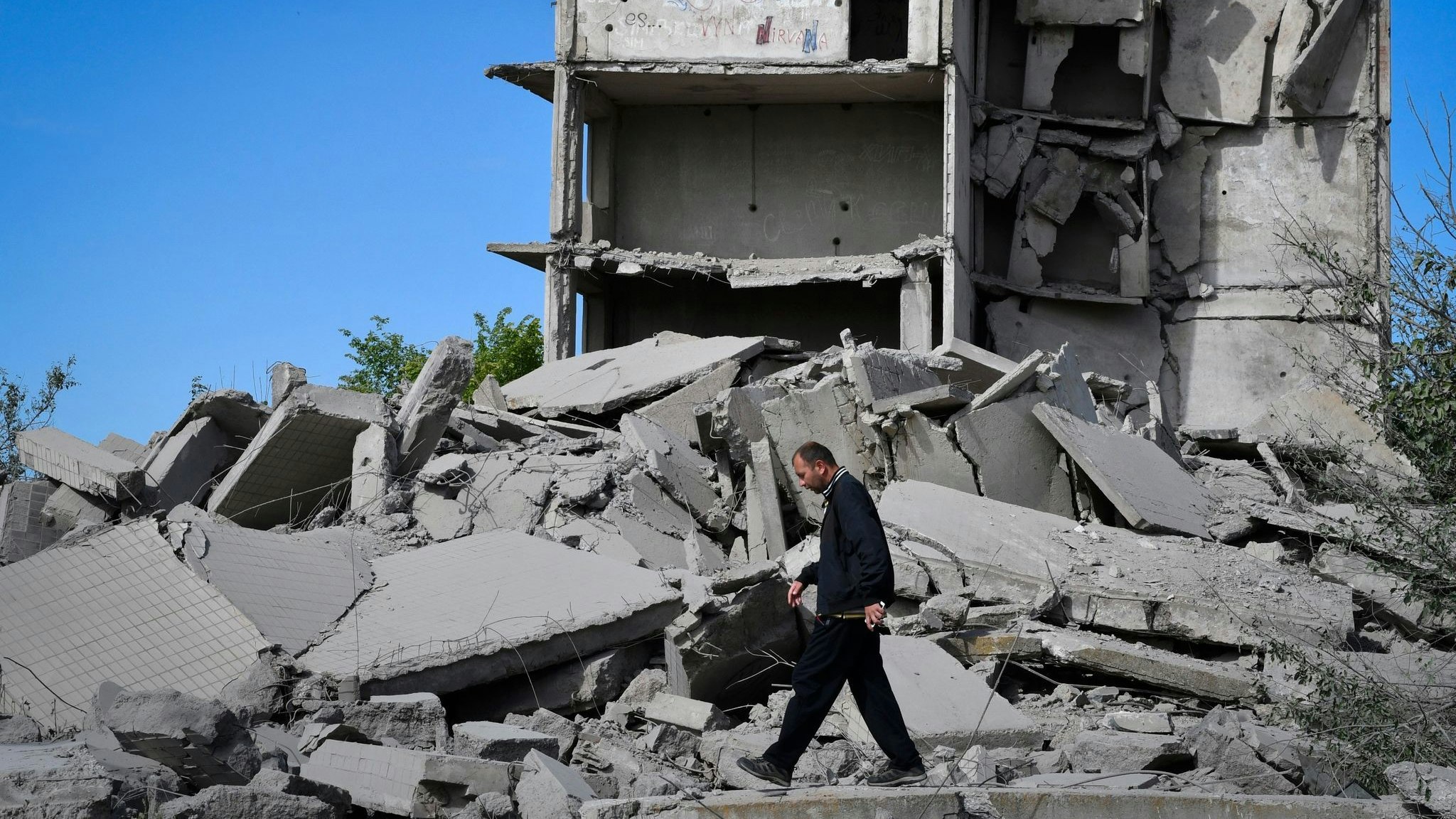 Ein Anwohner geht an einem durch russischen Beschuss zerstörten Haus vorbei. Foto: dpa/Andriyenko