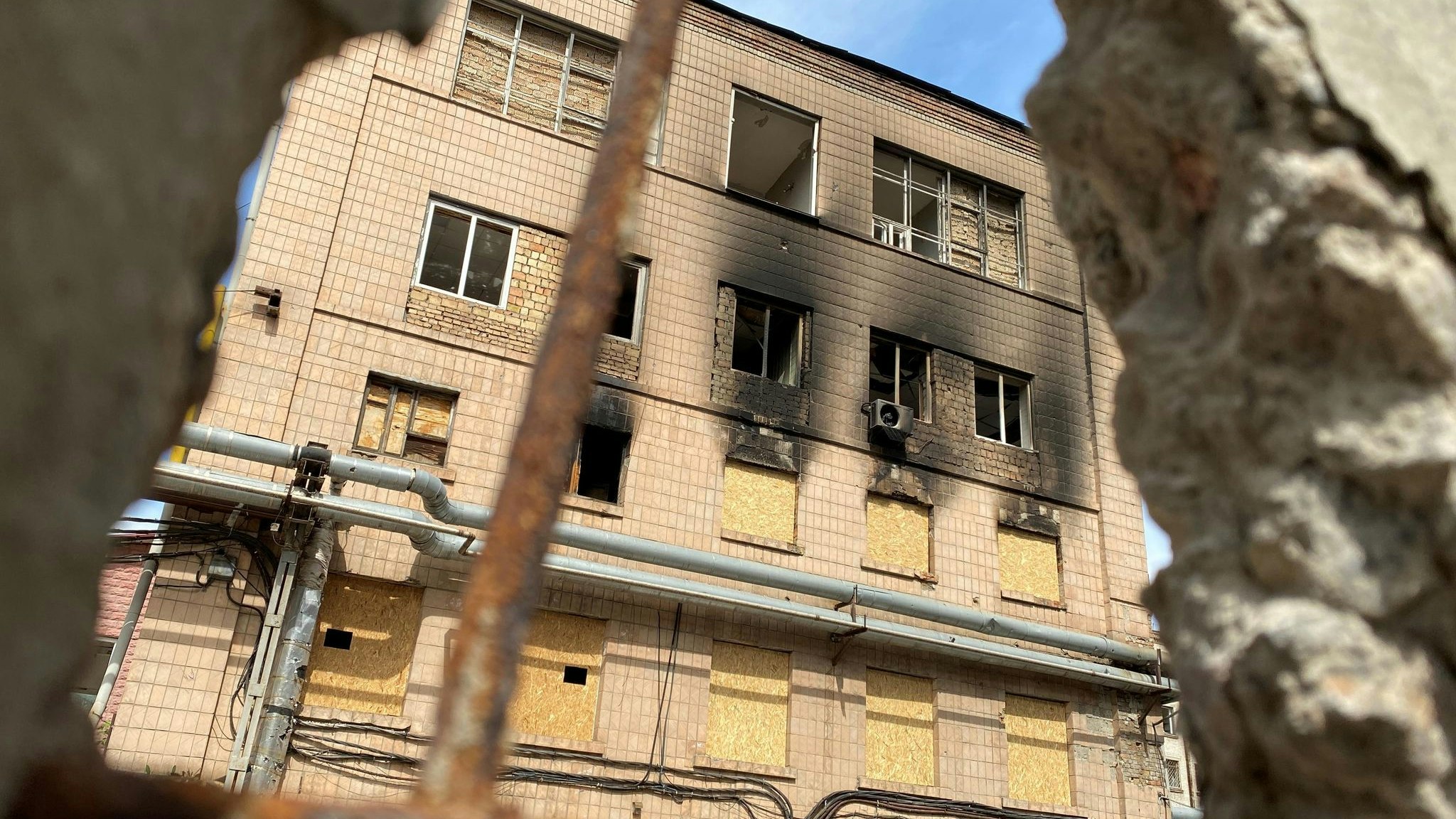 Durch ein Loch in einer zerstörten Mauer wird der Blick frei auf ein Fabrikgebäude in Kiew. Foto: dpa/Mauder