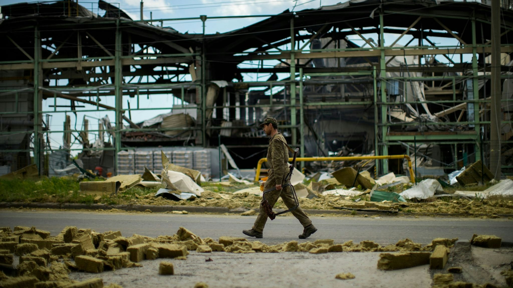 Ein ukrainischer Soldat geht an einer durch Beschuss zerstörten Fabrik vorbei. Foto: dpa/Seco