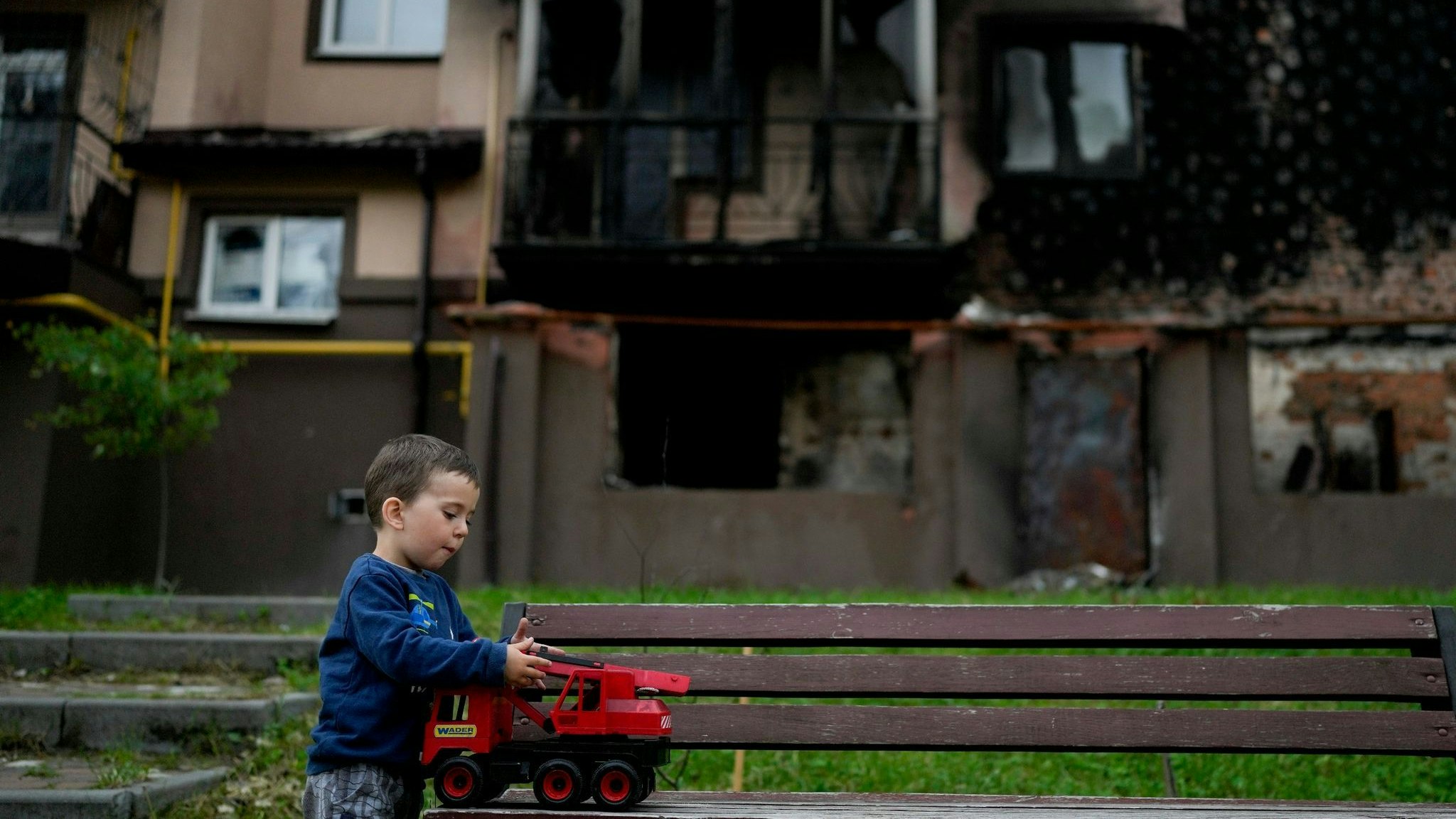 Vor einem zerstörten Gebäude in Irpin am Stadtrand von Kiew spielt der kleine Yarik mit seinem Spielzeug-Lastwagen. Foto: dpa/Pisarenko