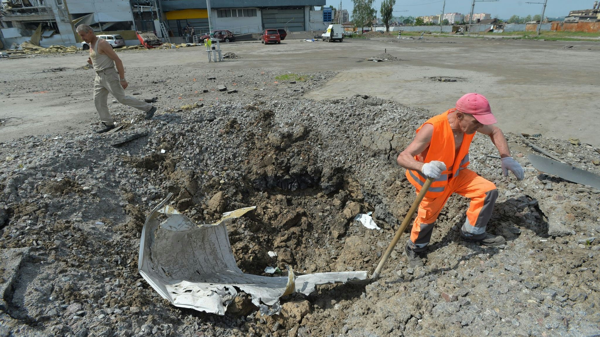 Ein Arbeiter beseitigt in Charkiw Rückstände aus einem Granatenkrater. Foto: dpa/Druk