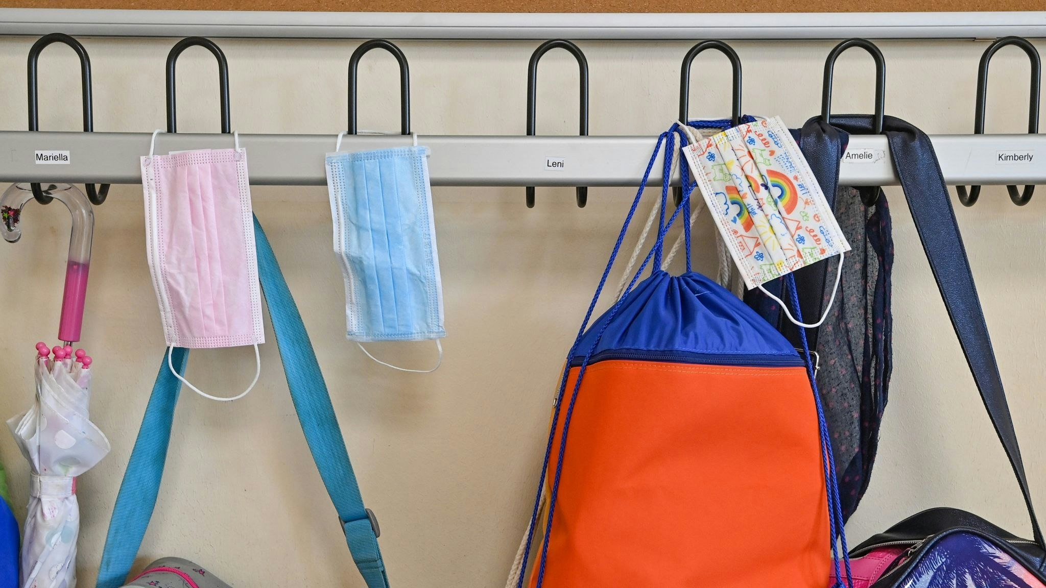 Medizinische Masken und Schultaschen hängen in einer Schulgarderobe. Foto: dpa/Pleul