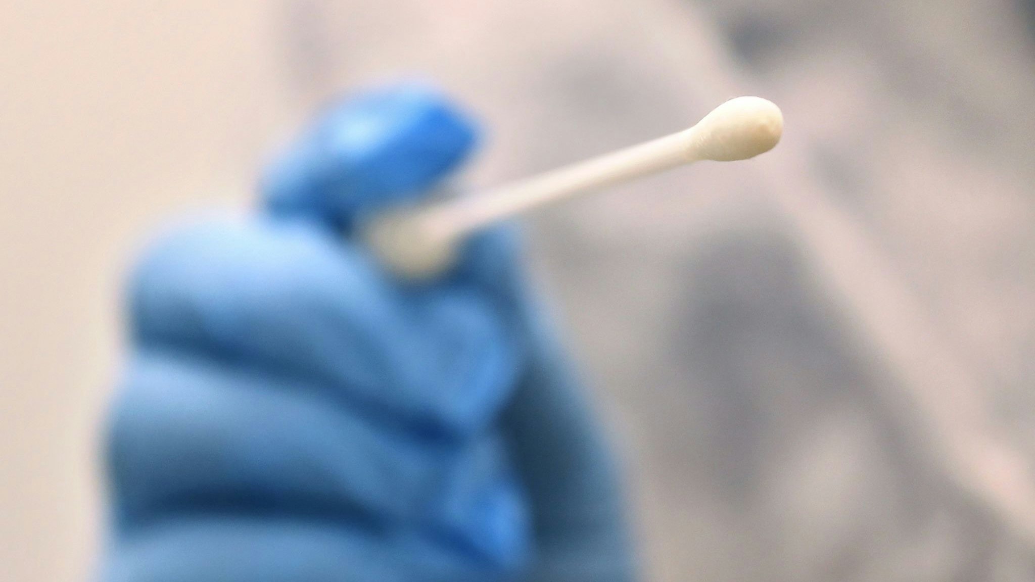 Ein Arzt hält einen Tupfer, mit dem ein Abstrich für einen Coronatest gemacht wird. Foto: dpa/Hildenbrand
