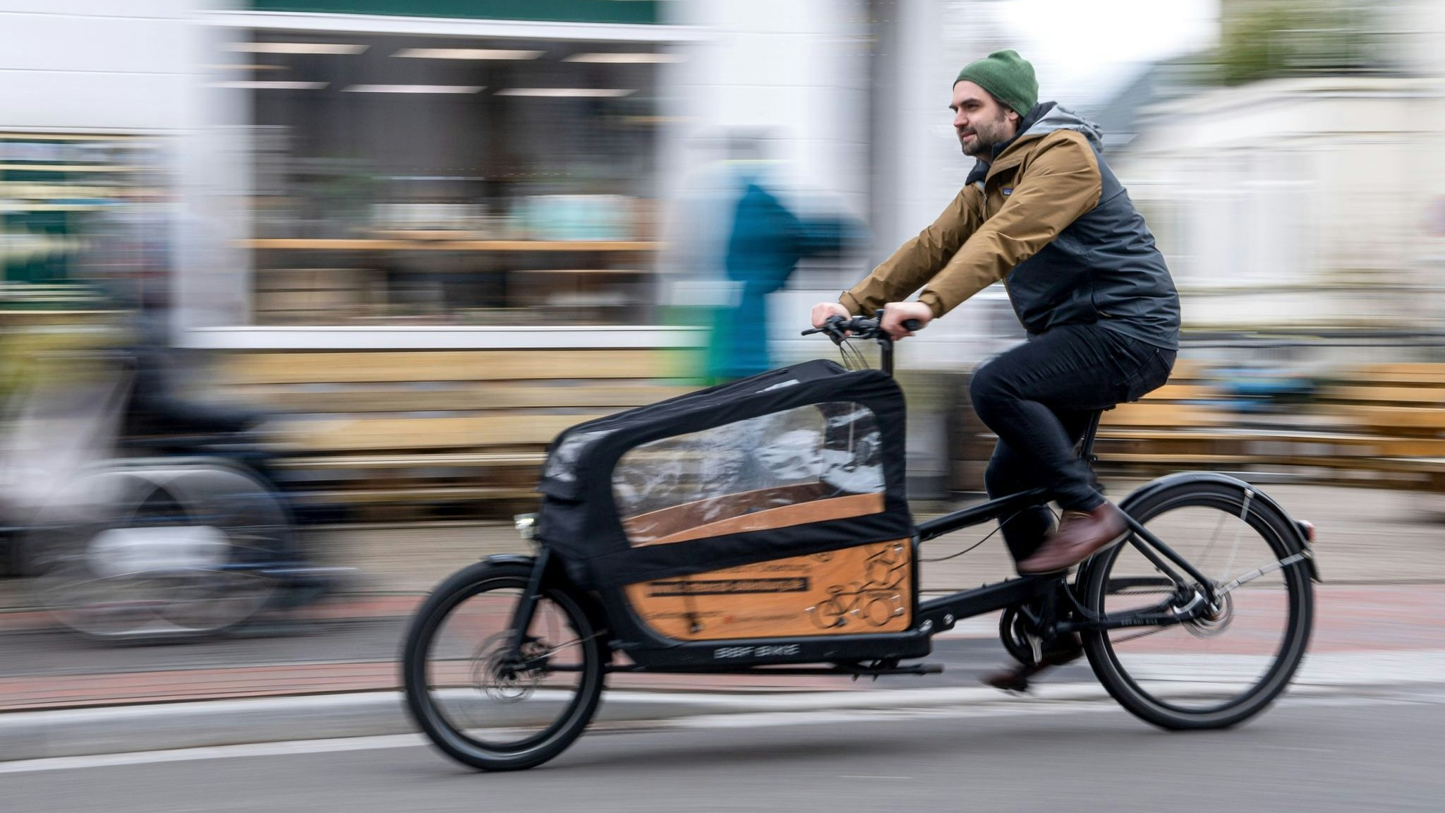 Ein Mann fährt mit einem Lastenrad durch die Stadt. Foto: dpa/Schuldt