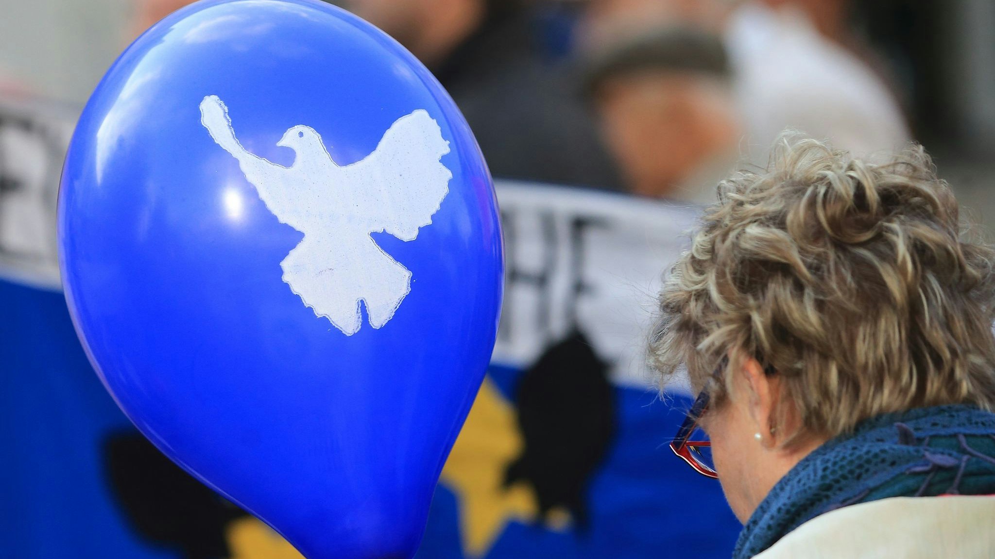 Ein blauer Luftballon mit dem Symbol einer weißen Friedenstaube wird getragen. Foto: dpa/Wolf