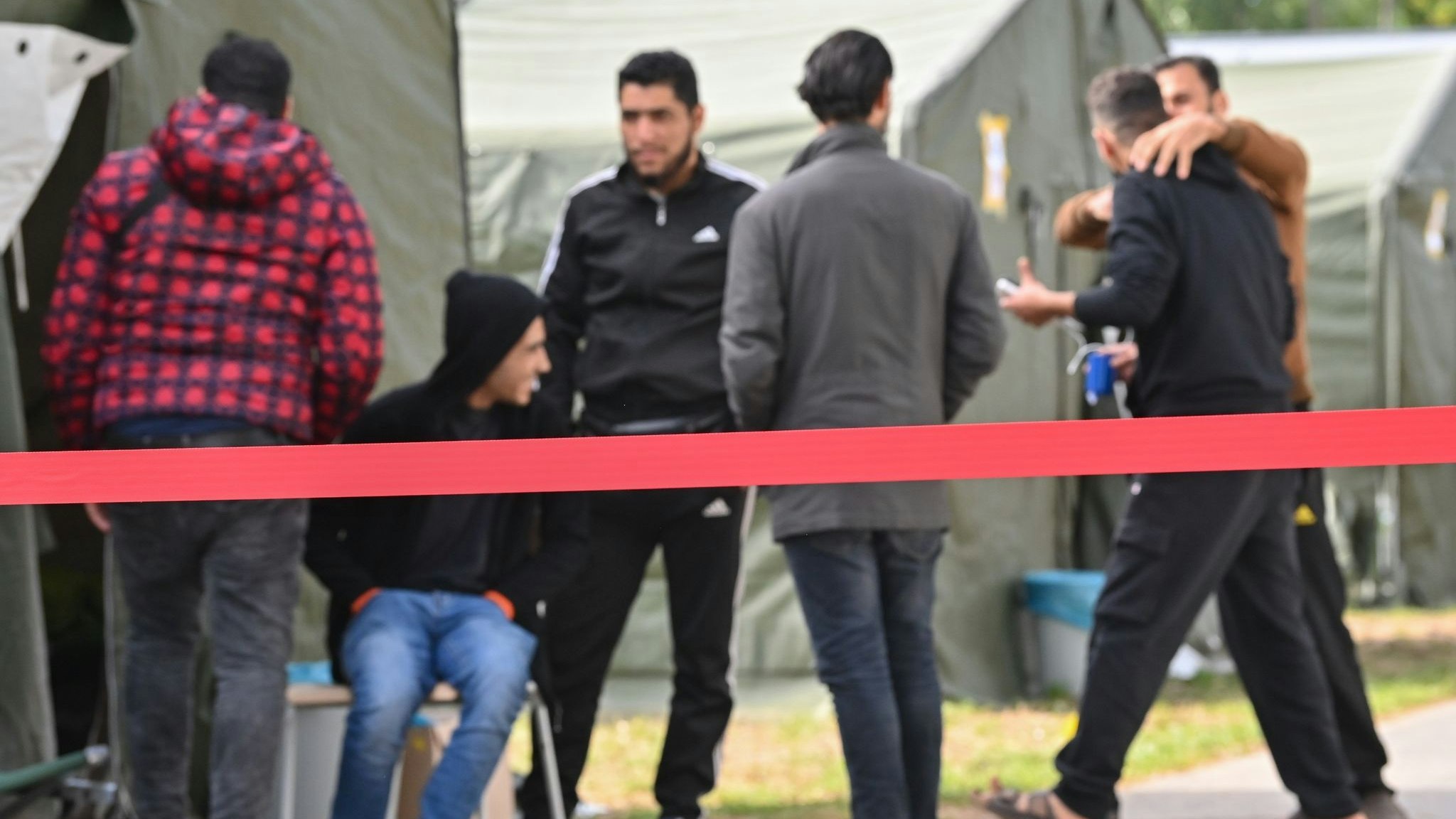 Migranten sind vor Zelten in der Zentralen Erstaufnahmeeinrichtung für Asylbewerber (ZABH) des Landes Brandenburg zu sehen. Foto: dpa/Pleul