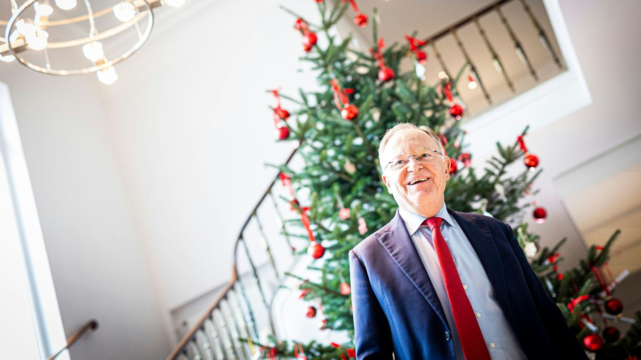 Stephan Weil (SPD), Ministerpräsident von Niedersachsen, steht lächelnd vor einem Weihnachtsbaum. Foto: dpa/Frankenberg