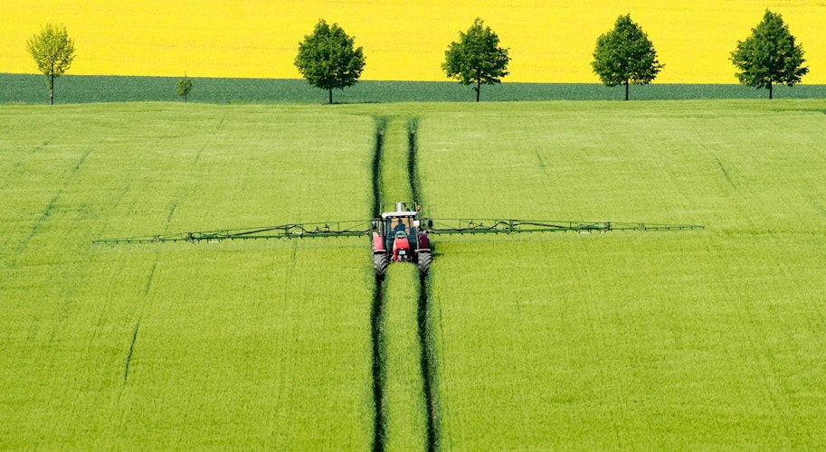 Ein Landwirt fährt mit einem Traktor über ein Gerstenfeld im Landkreis Wolfenbüttel und versprüht Pflanzenschutzmittel. Foto: dpa