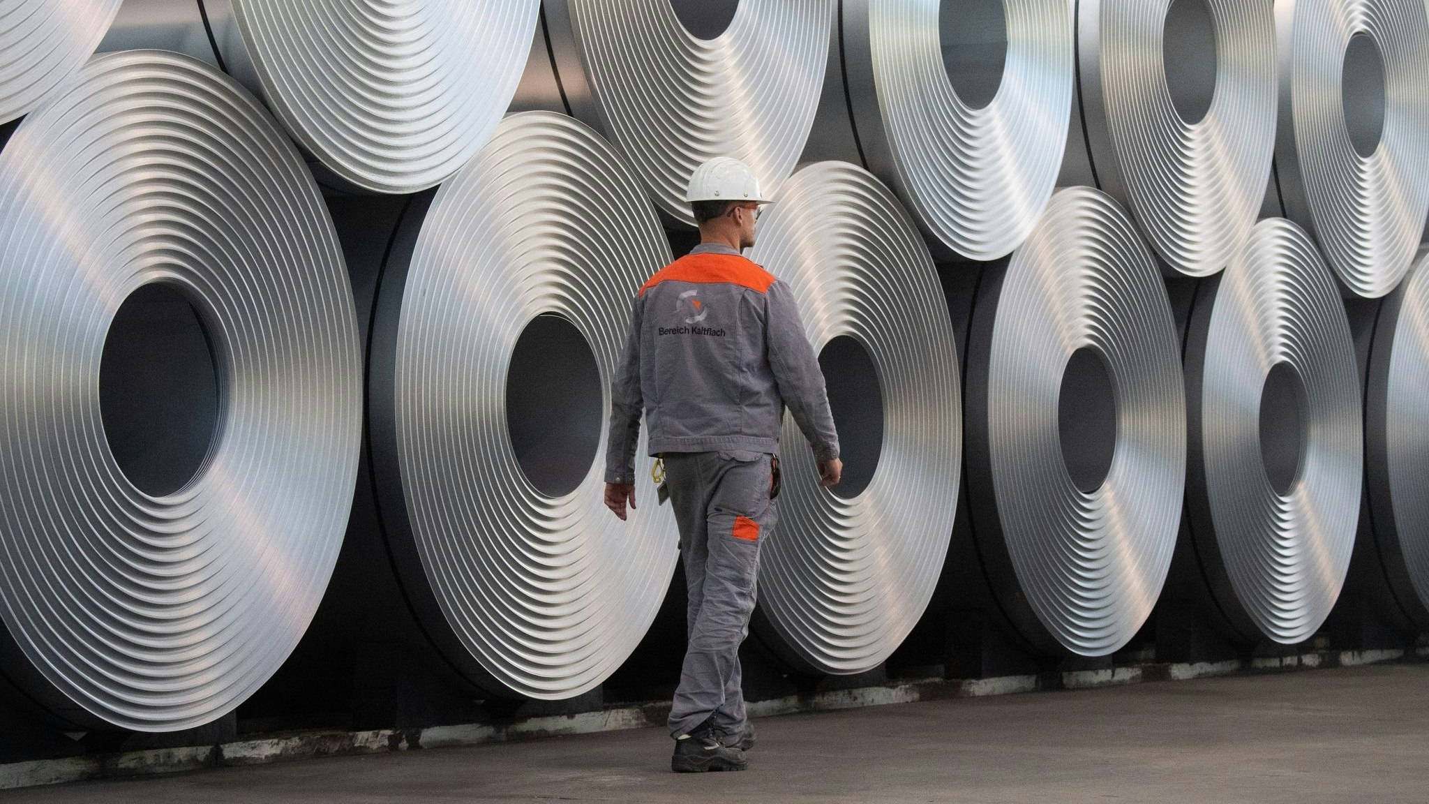 Ein Mitarbeiter geht bei der Salzgitter AG an aufgewickeltem Stahl (Coils) entlang. Die deutsche Industrie hat sich etwas von ihrem schwachen Auftakt ins Schlussquartal 2022 erholt. Foto: dpa/Stratenschulte