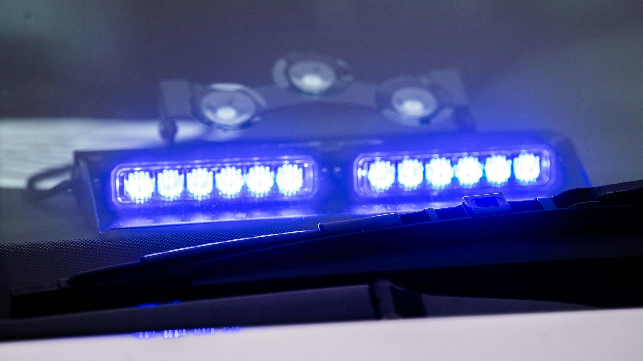 Ein Blaulicht leuchtet unter der Frontscheibe eines Einsatzfahrzeugs der Polizei. Foto: dpa/Mirgeler