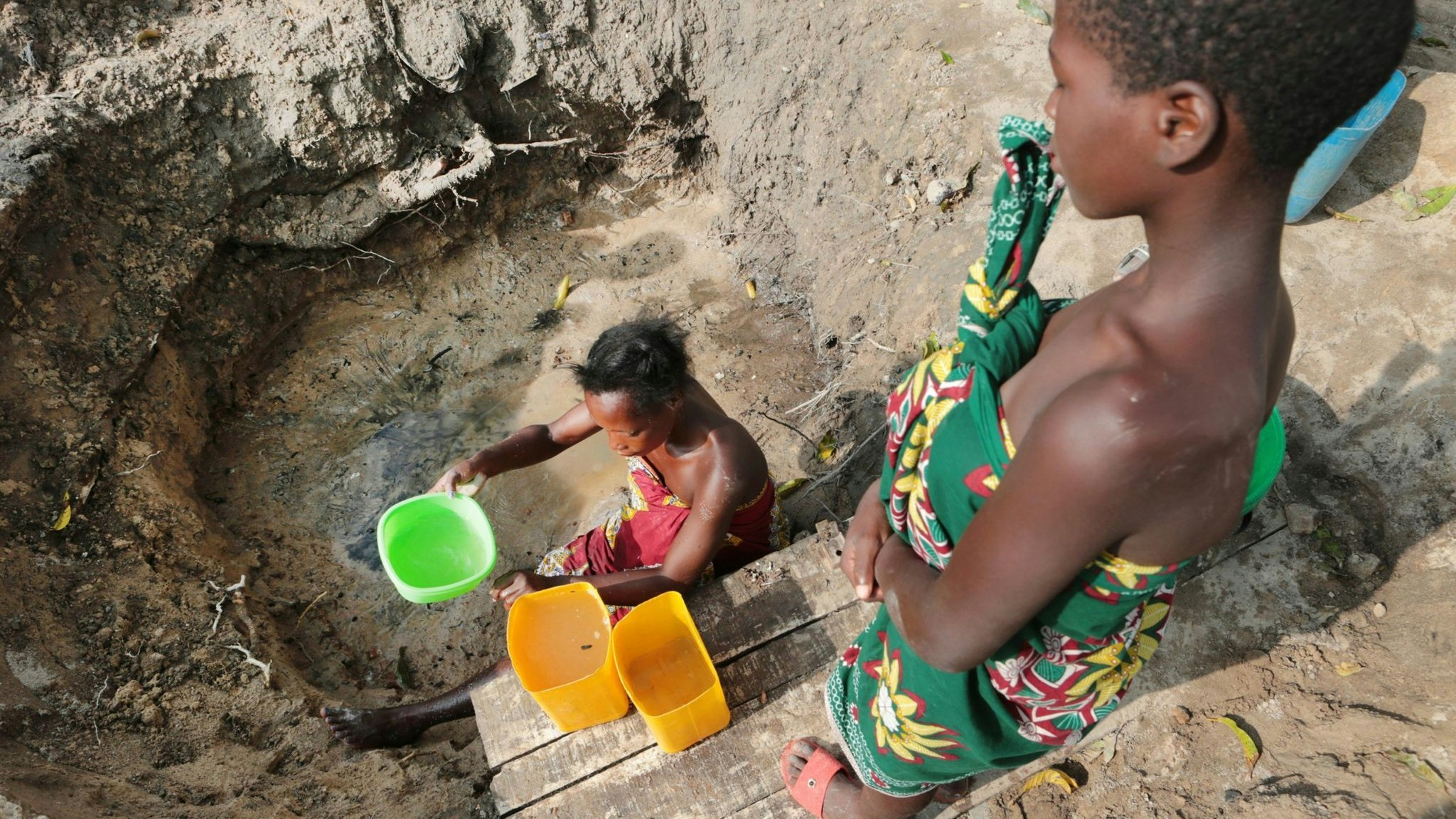 Eine Frau schöpft in Mosambik Wasser aus einer ungeschützten Quelle. Foto: dpa/Mukwazhi