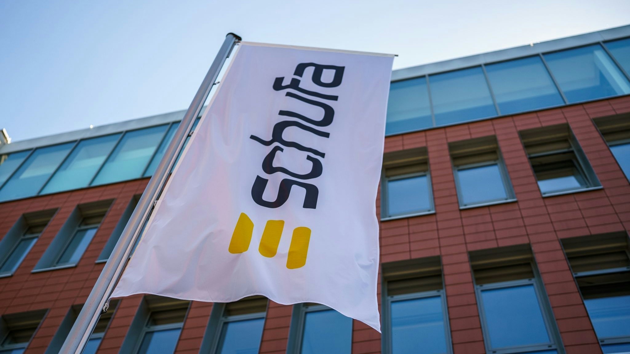 Eine Flagge mit dem Firmenlogo flattert vor dem Geschäftssitz der Schufa in Wiesbaden. Foto: dpa/Arnold