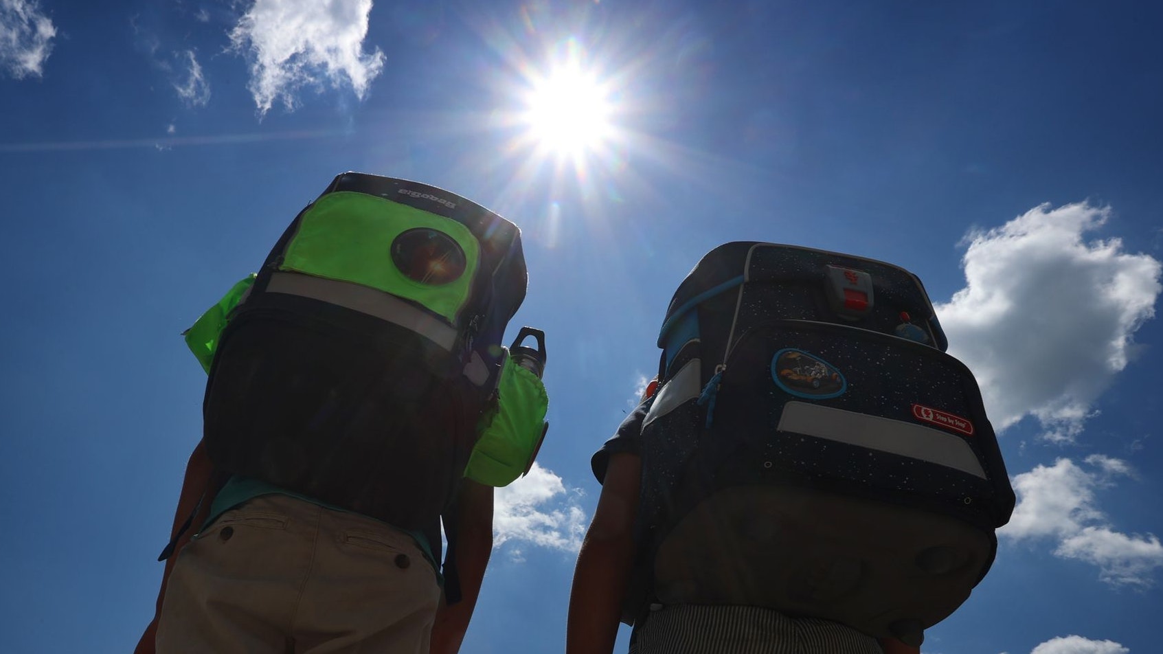 Zwei Kinder laufen mit ihren Büchertaschen im Sonnenschein. Foto: dpa/Hildenbrand