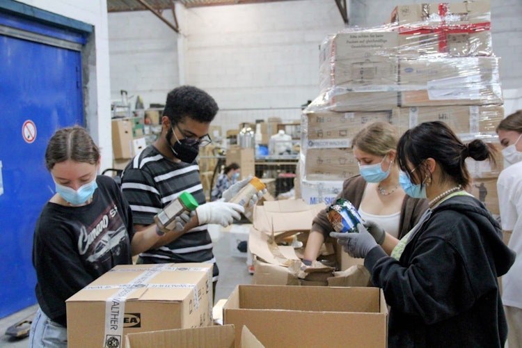 Freiwillige Helfer packen die Lieferungen aus Deutschland aus. In den Kartons befinden sich auch Lebensmittel. Foto: Vechta Cares
